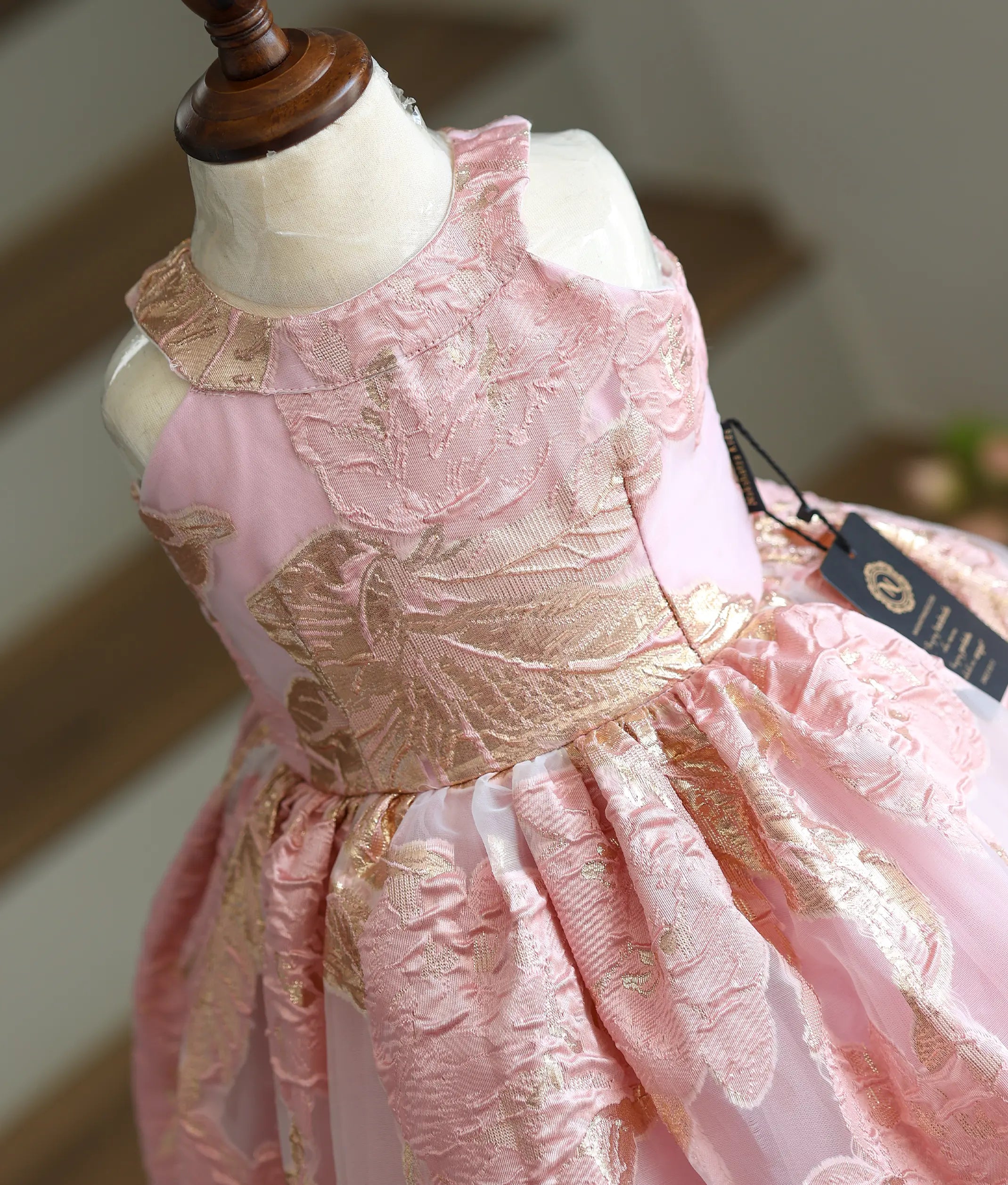 Close-up of the gold floral patterns and halter neck straps on the Turkish organza fabric.