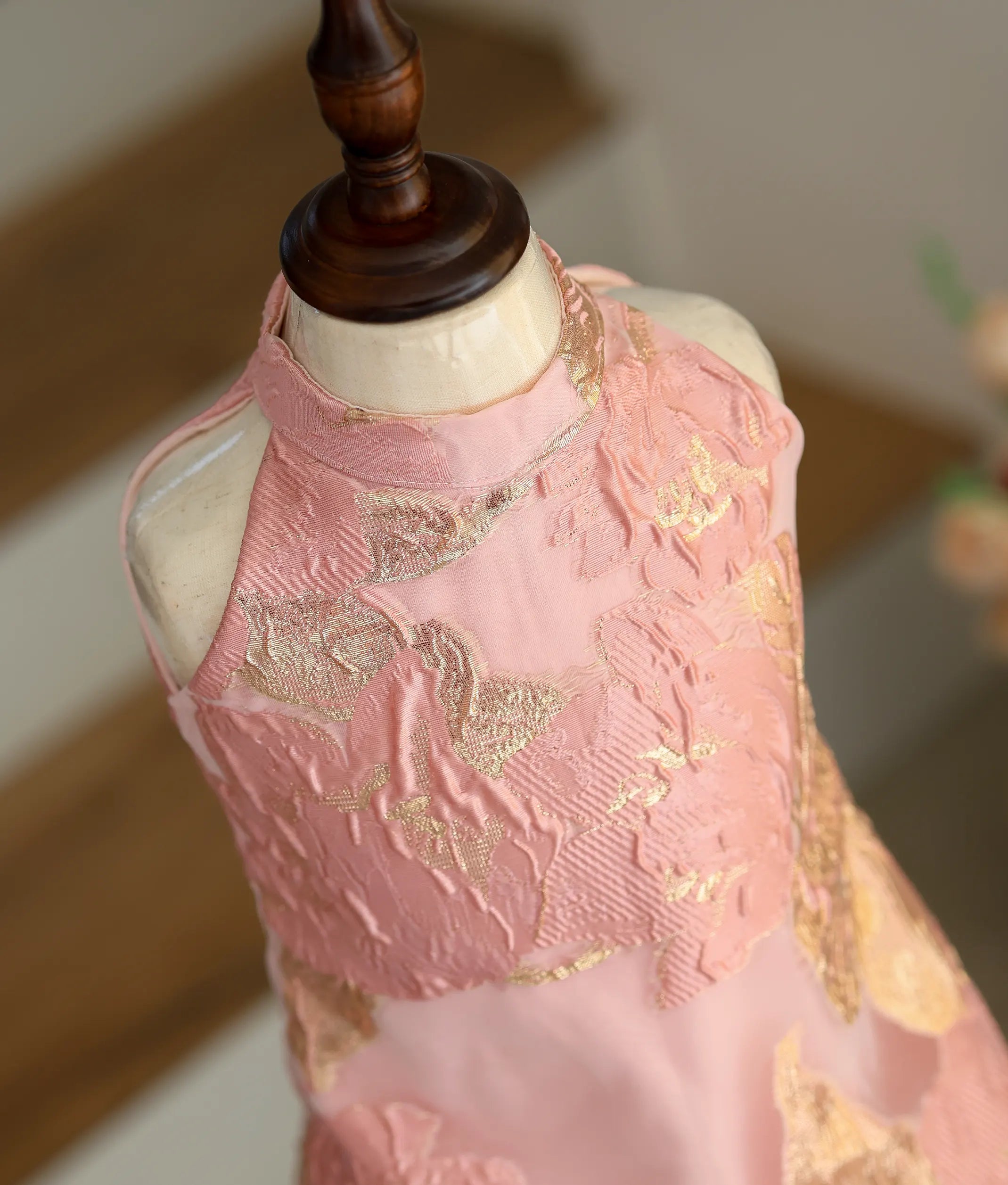 Close-up of the textured pink-gold leaf pattern and high-neck detailing on the Turkish organza frock.