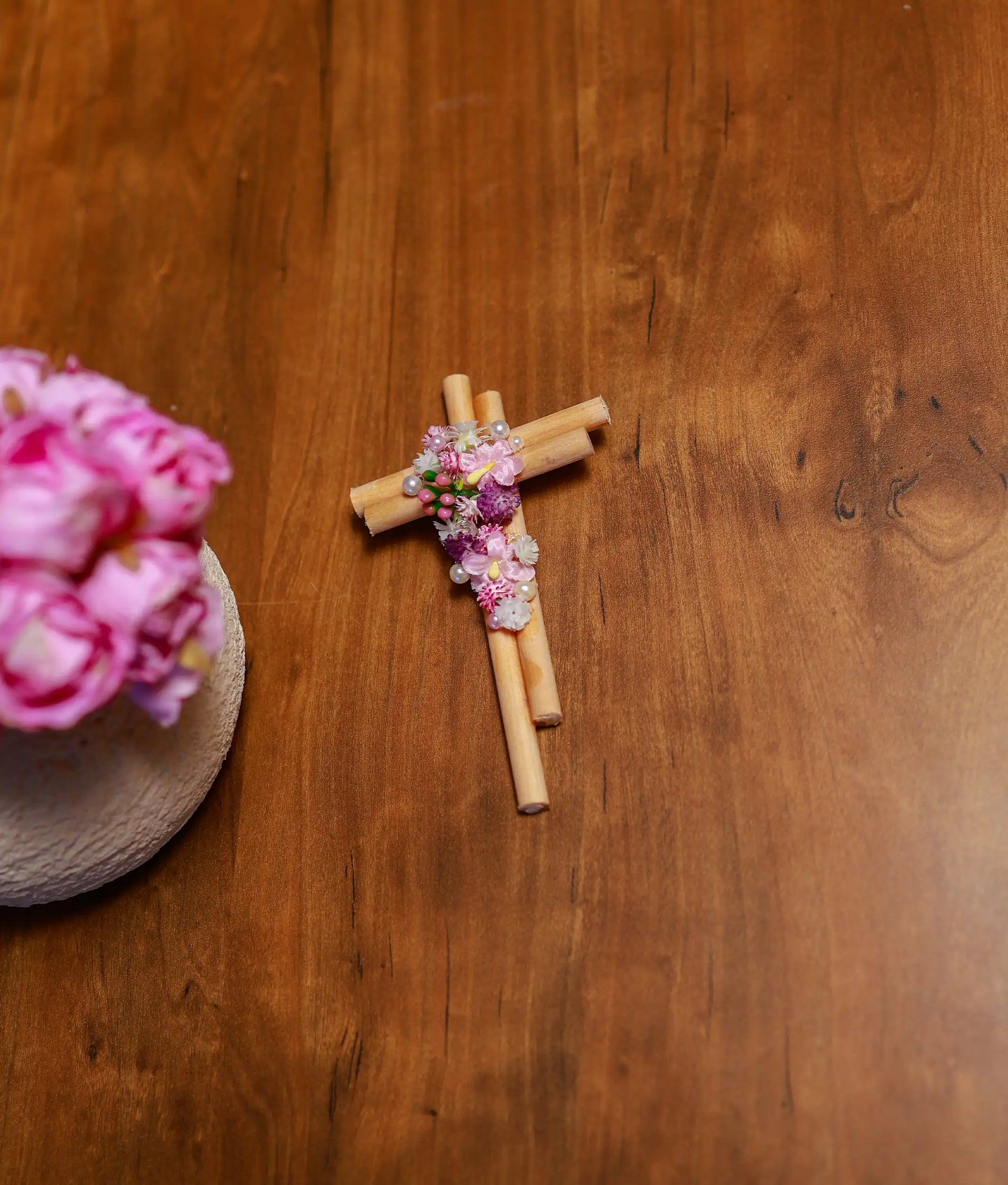 Front view of a handcrafted wooden baptism cross decorated with pink and white flowers and pearls