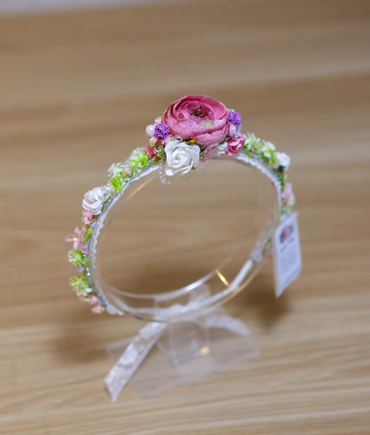 Front view of a pink and white floral handmade tiara for girls on a flexible white band