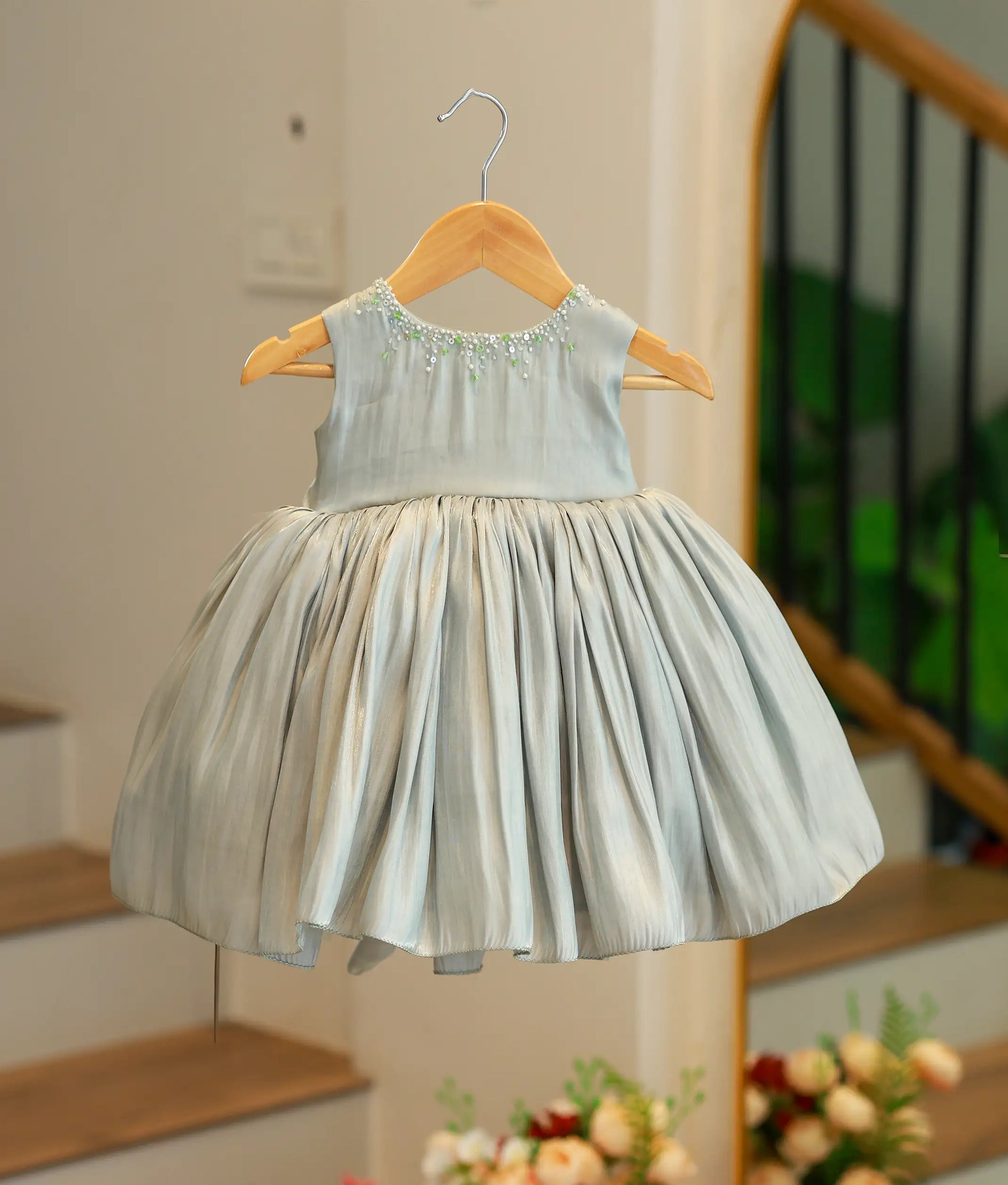 Front view of a green tulle net birthday frock for girls featuring butterfly ruffled sleeves, a pearl-scattered bodice, and a multi-layered skirt with a ruffled hem.