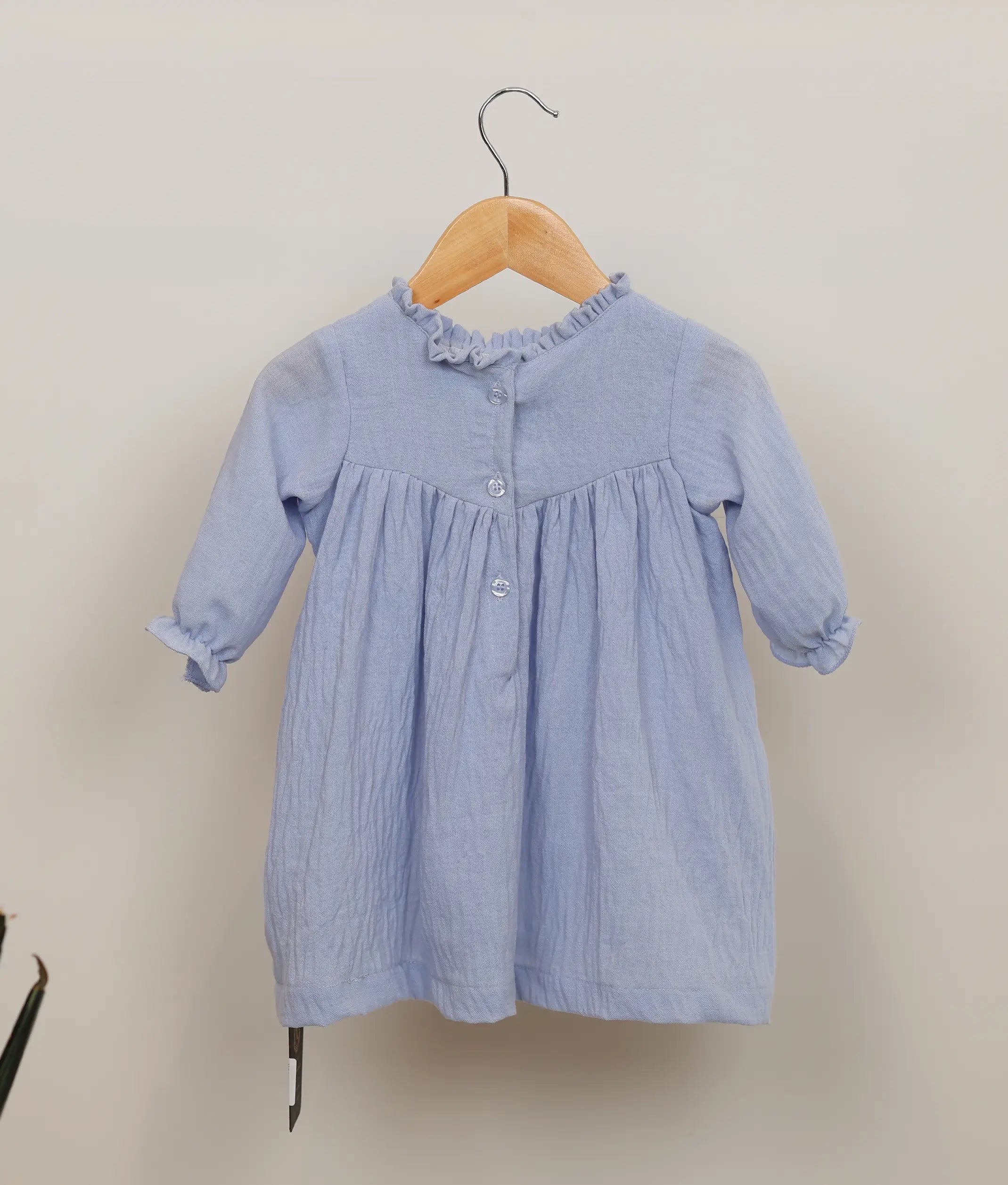 Back view of an blue linen frock with pleated and flared skirt, suitable for formal occasions.