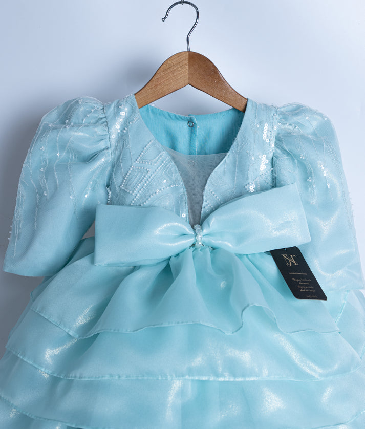 Close-up of the powder blue dress bodice showing the crystal bow at the waist and sheer long puff sleeves
