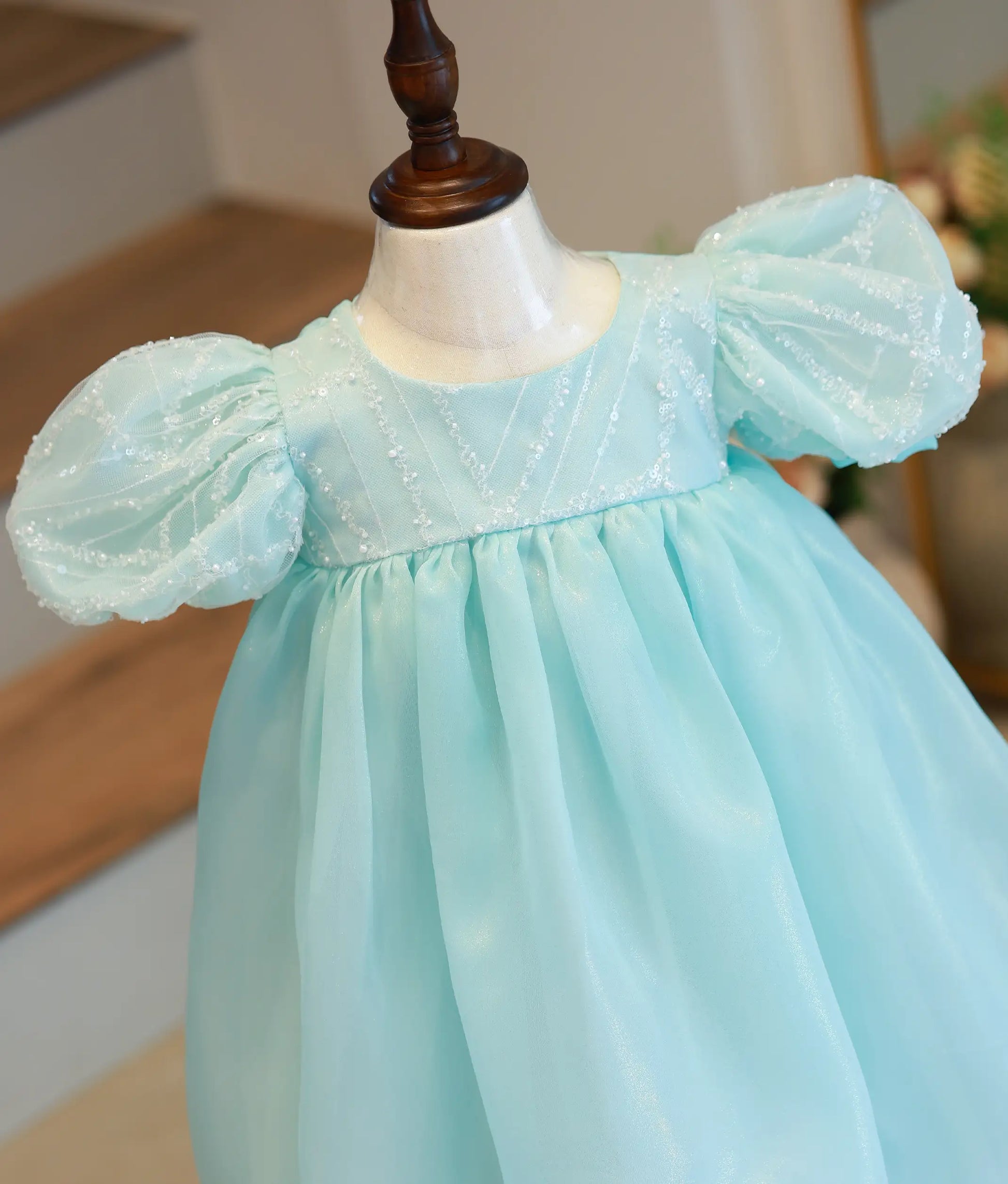 Close-up of the powder blue dress showing the sequined yoke, shimmer fabric, and puff sleeve with sequined cuff