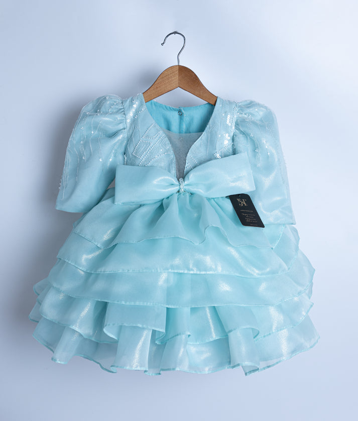 Front view of a powder blue shimmer organza princess theme dress with tiered skirt and crystal bow