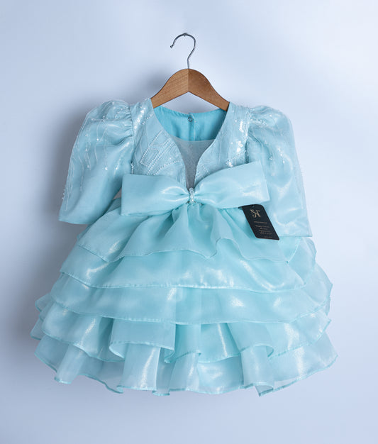 Front view of a powder blue shimmer organza princess theme dress with tiered skirt and crystal bow