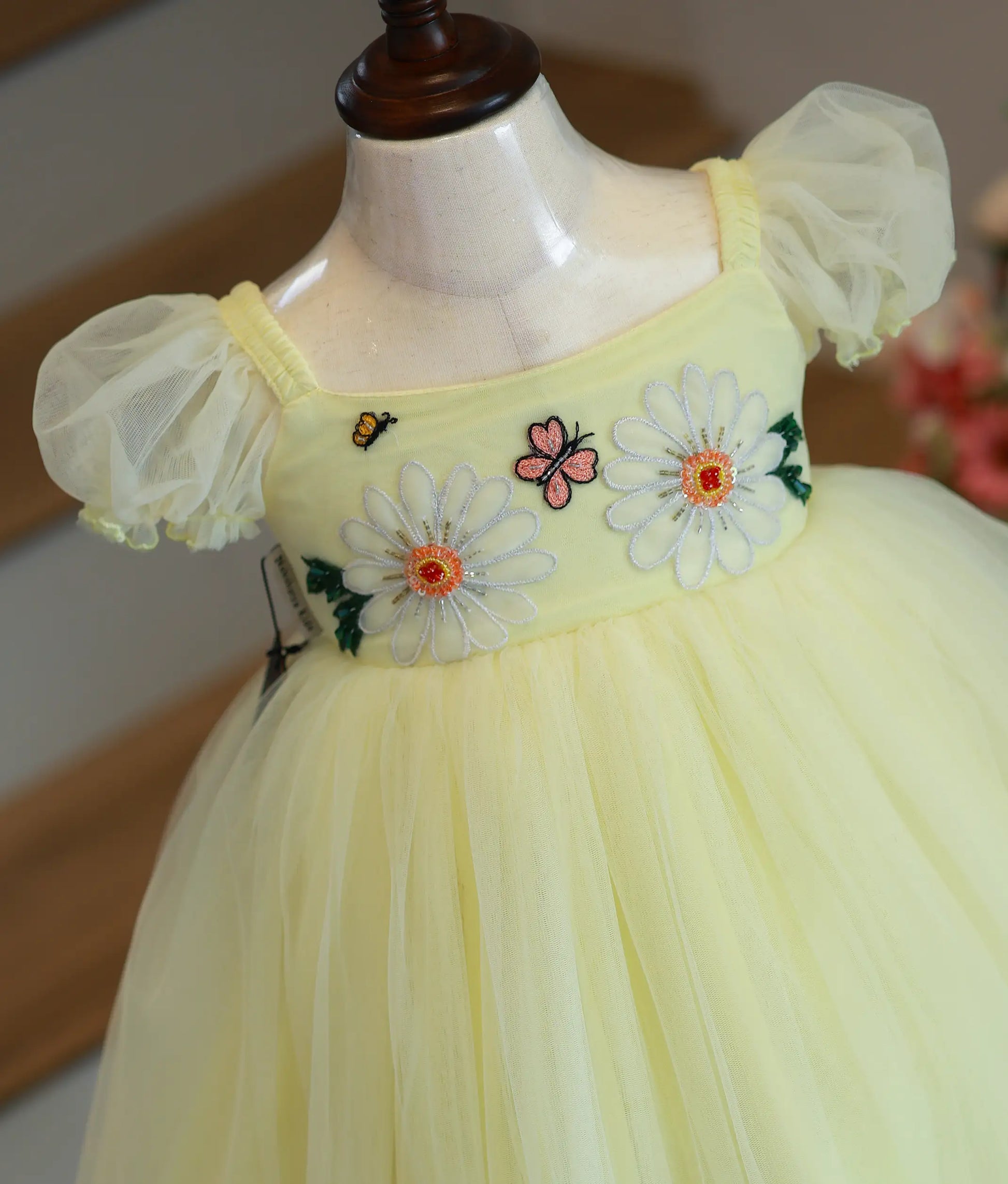 Close-up of floral embroidery detail on powder yellow tulle net frock for baby girl