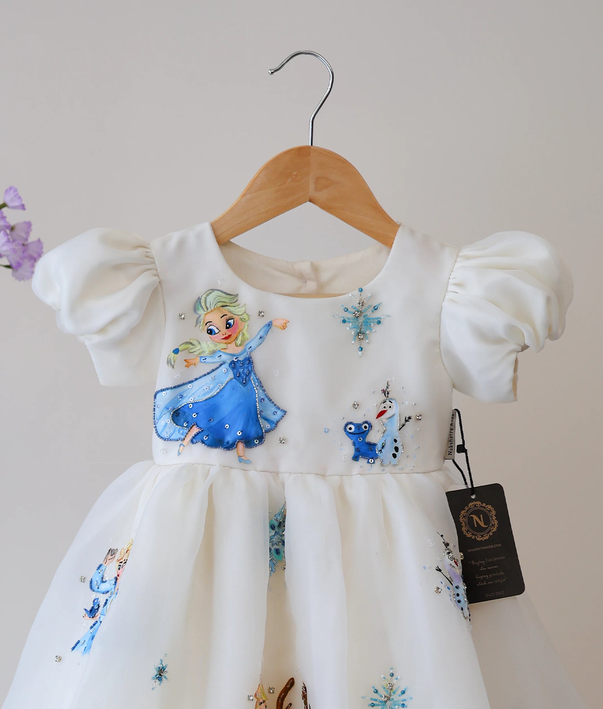 Close-up of the hand-painted Disney characters and snowflake motifs on the off-white organza birthday dress