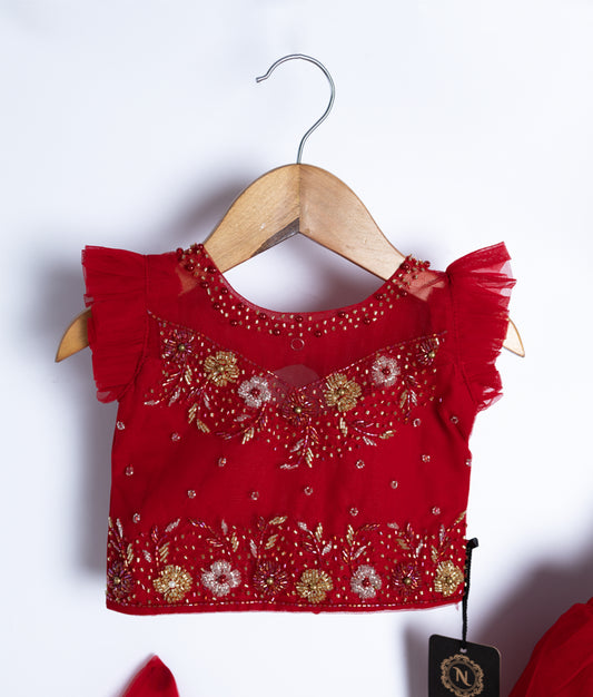 Close-up of red baby dress top with gold embroidery and ruffled sleeves