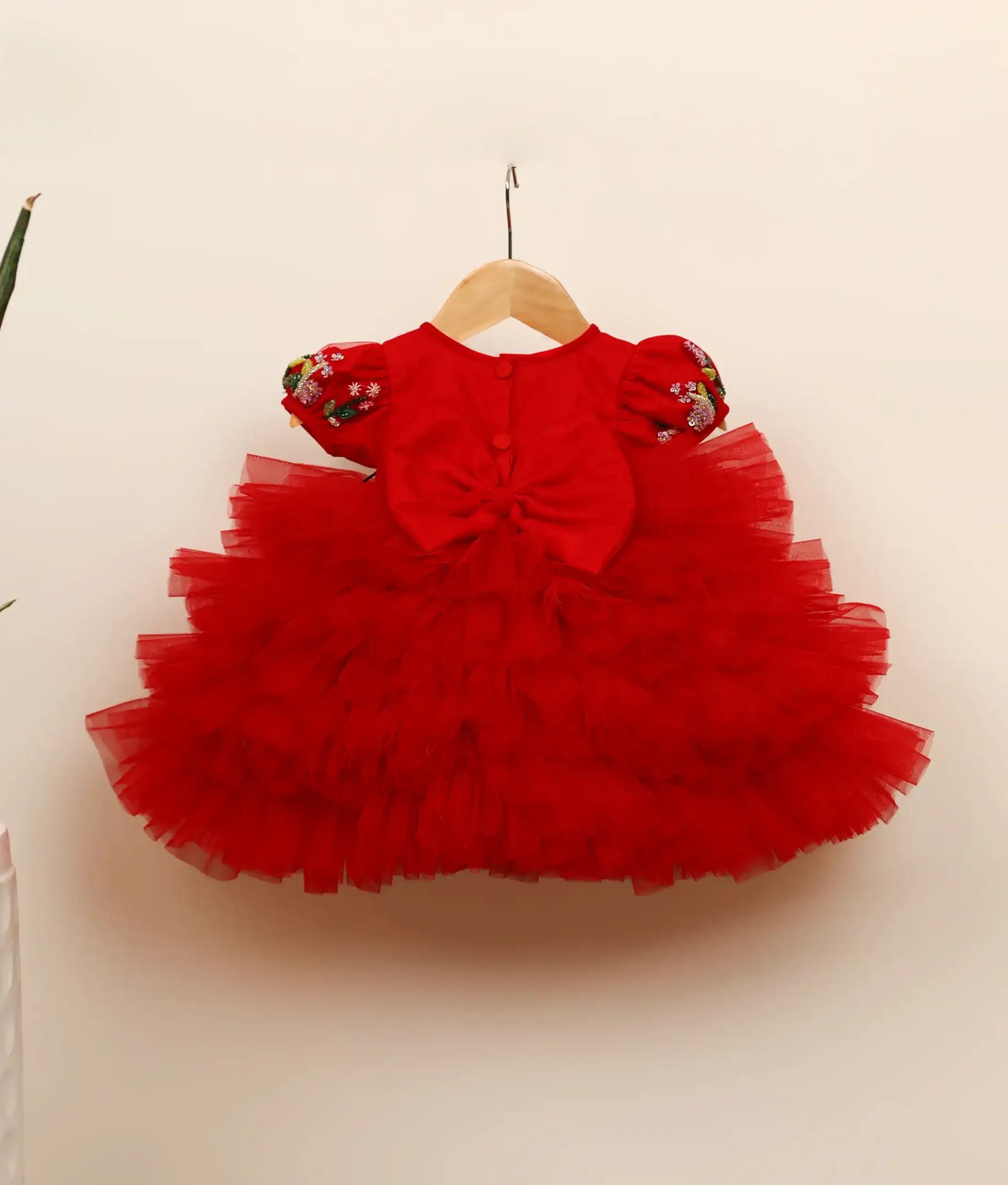 Back view of the red butterfly theme dress showing the round neck, show button, and decorative bow