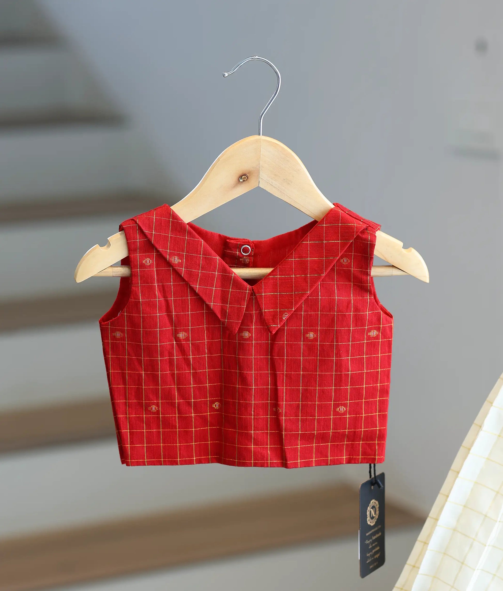 Close-up showing the gold checked pattern and collar on the red top.