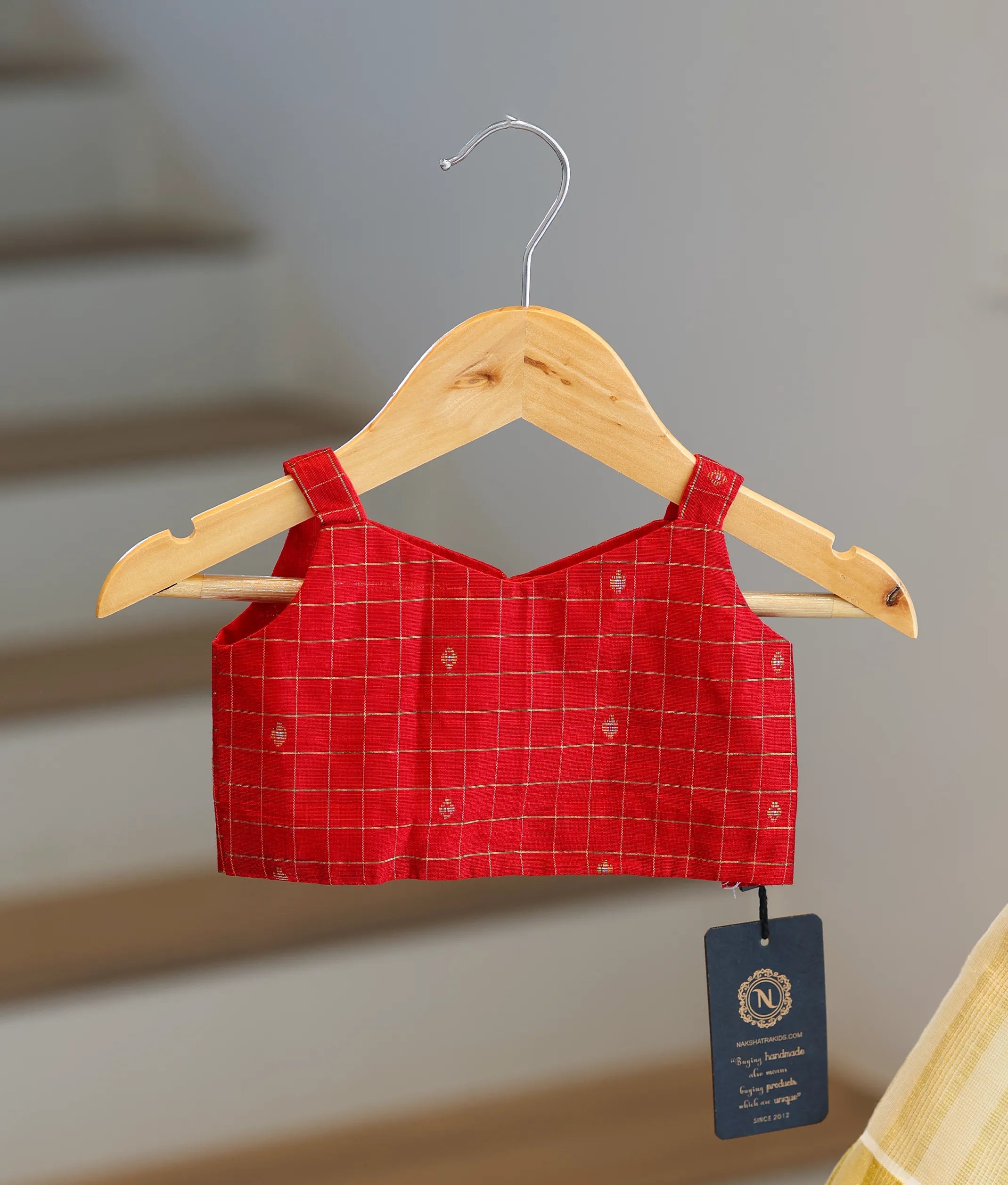 Close-up showing the gold checked pattern and traditional motifs on the red top.
