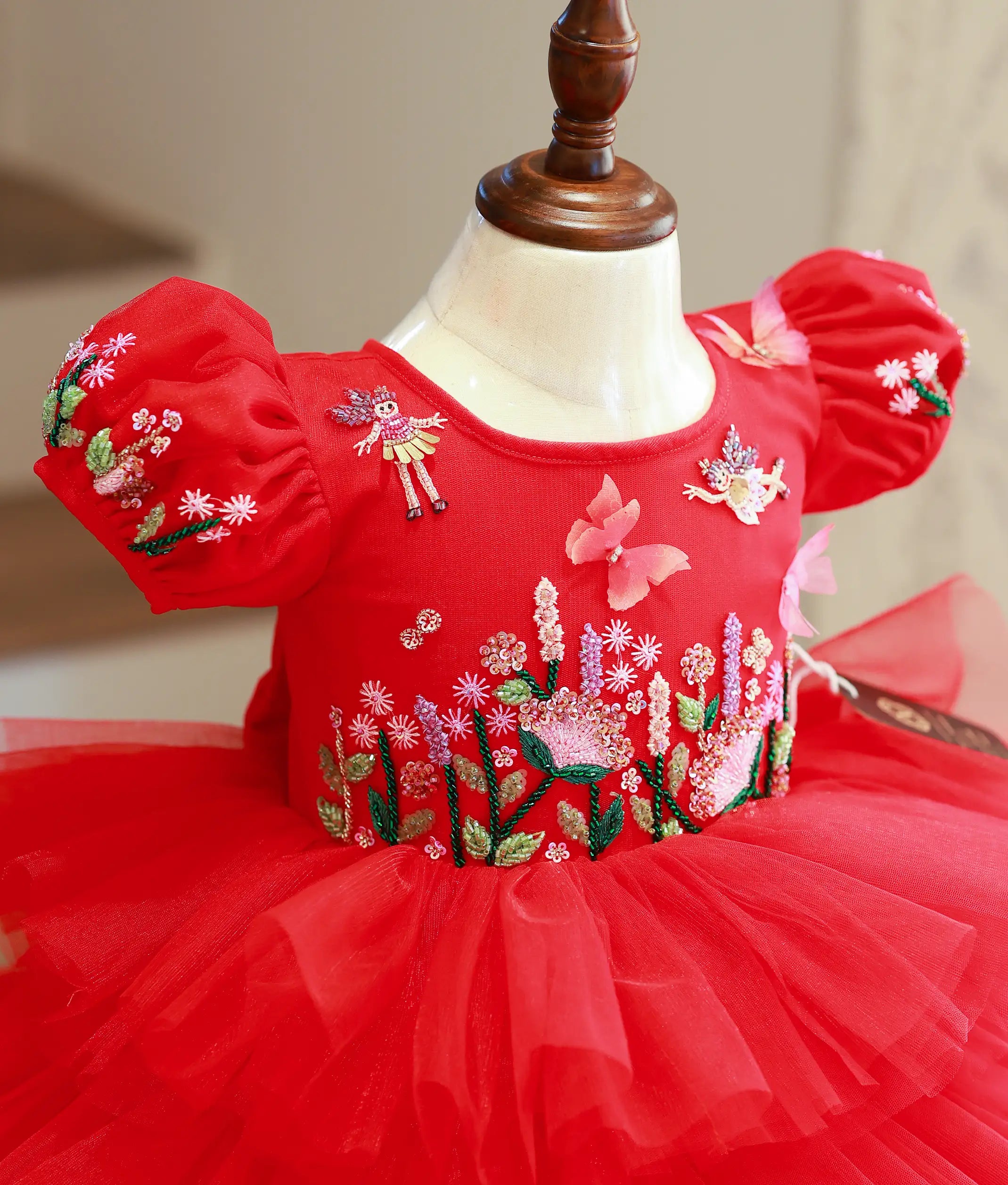 Close-up of the colorful butterfly and floral hand-embroidery with sparkly sequins on the red birthday dress