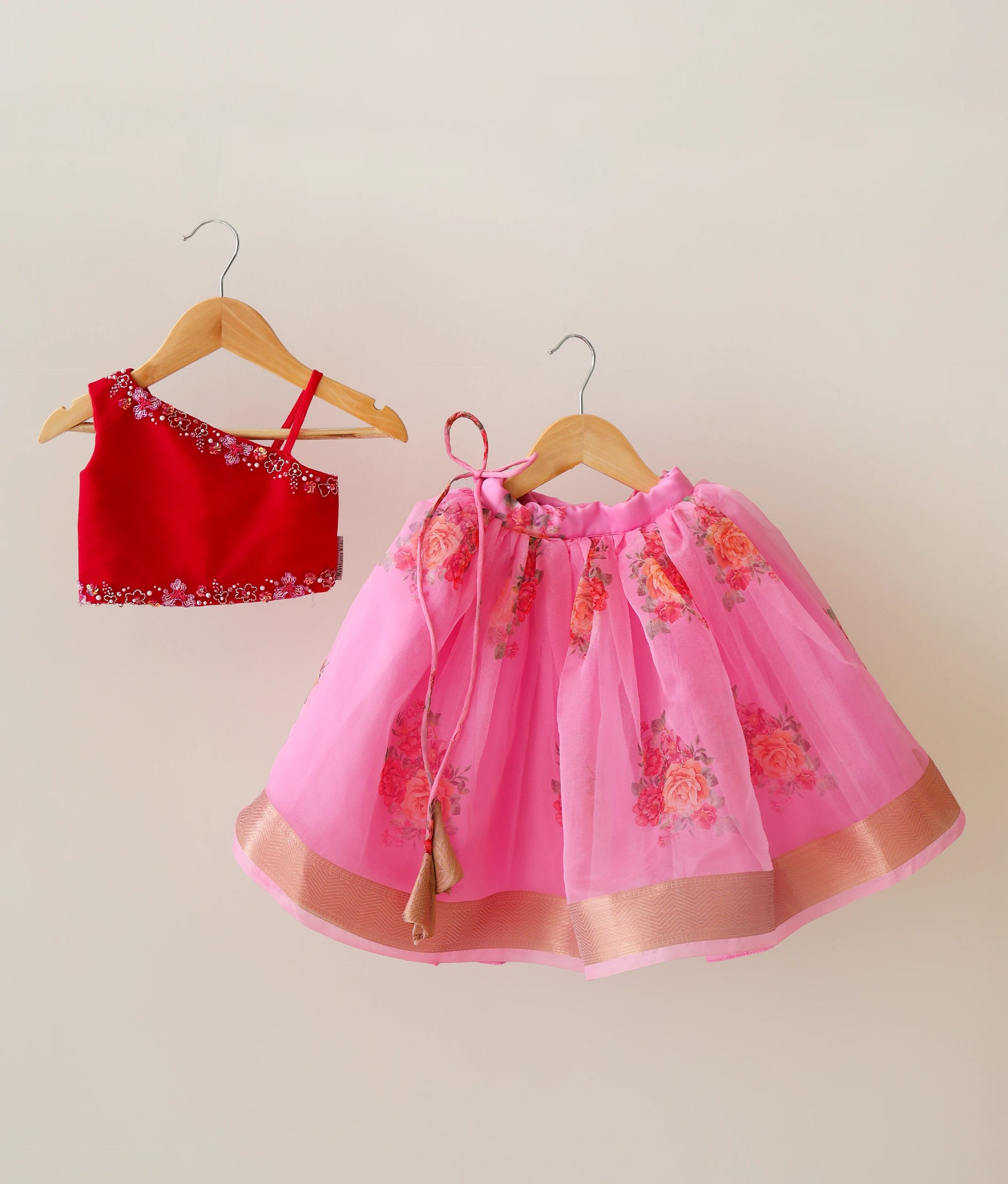 Front view of the red tulle net handworked top and pink floral organza skirt lehenga set for girls, showing the golden zari border