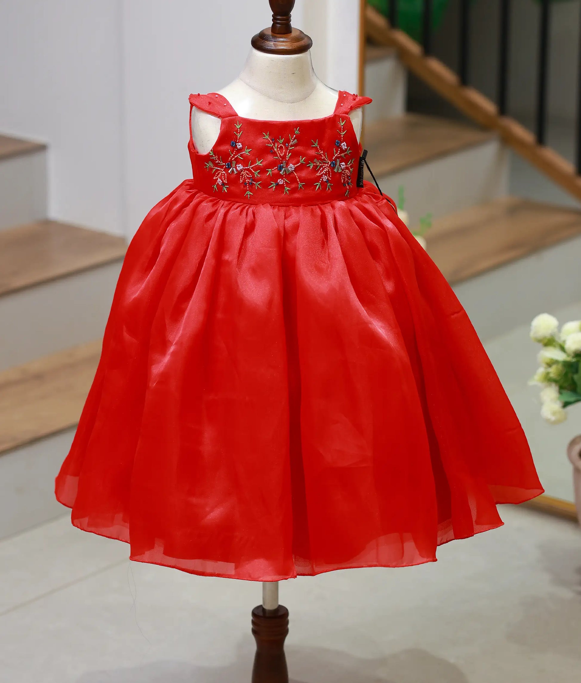 Front view of a red plain organza birthday gown for baby girls with floral hand embroidery and a full flowing skirt