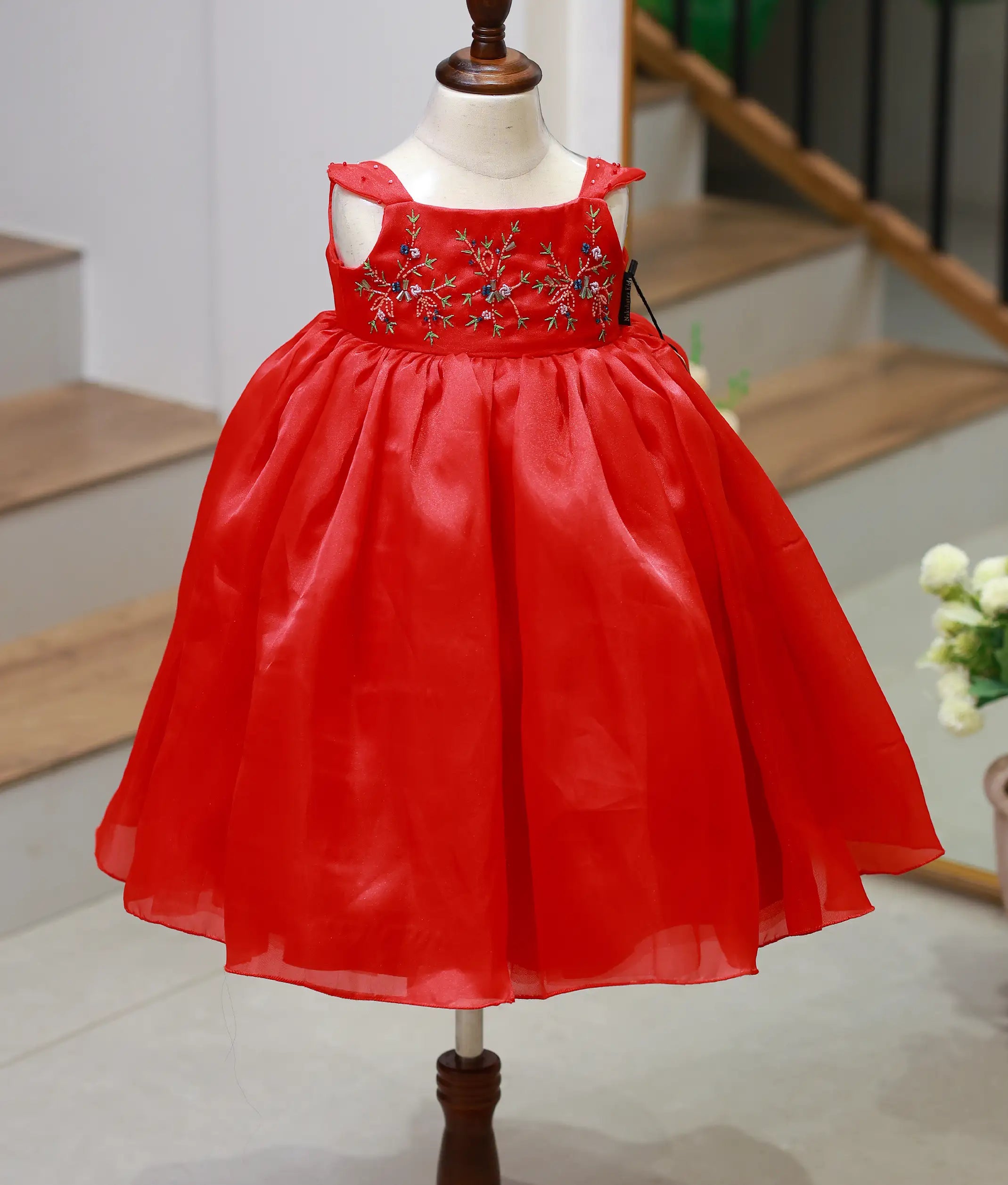 Front view of a red plain organza birthday gown for baby girls with floral hand embroidery and a full flowing skirt