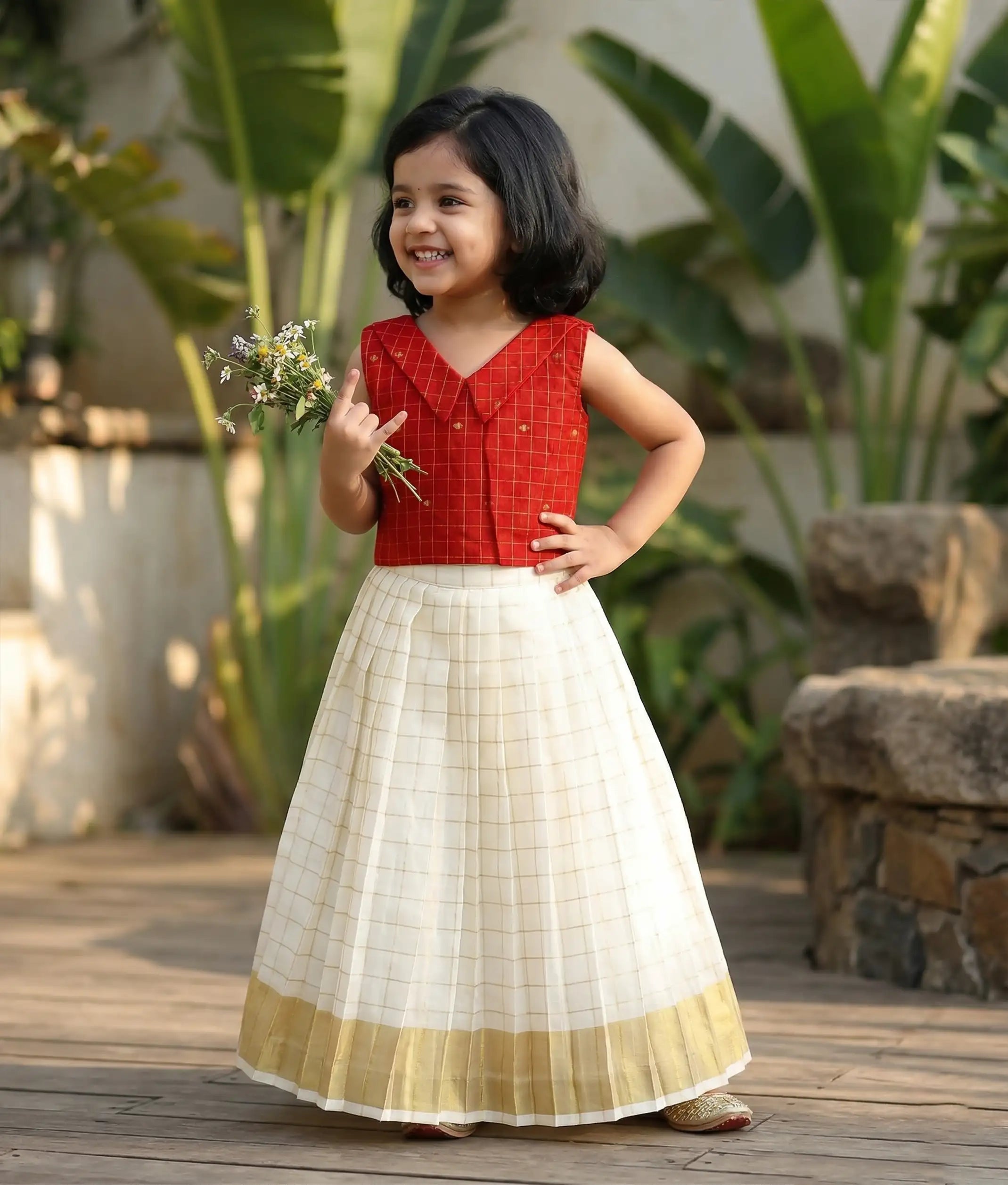 Baby girl wearing a traditional-style red top with a kasavu skirt.