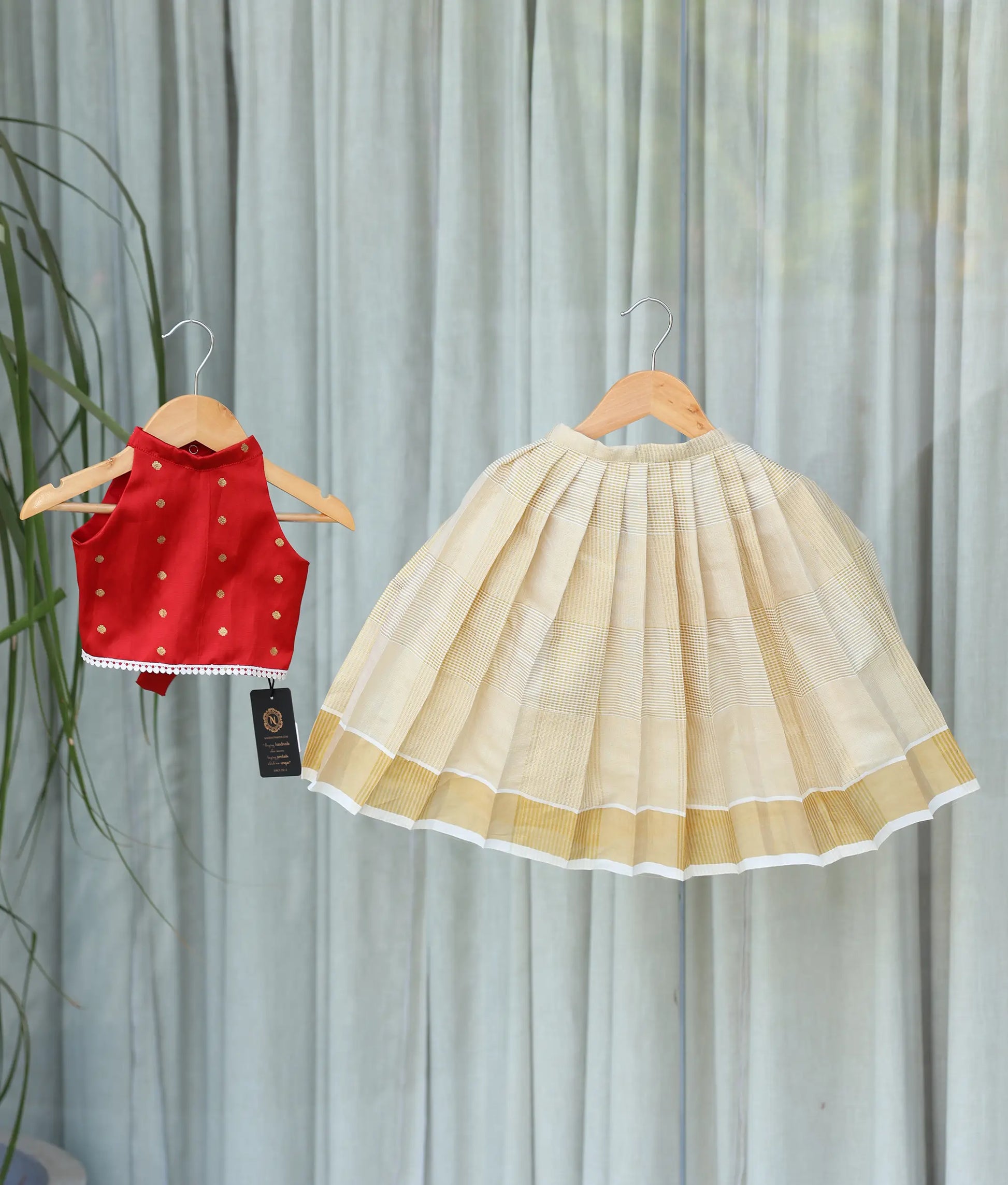Front view of a girl's red skirt and top set with a polka-dot design top and kasavu skirt.