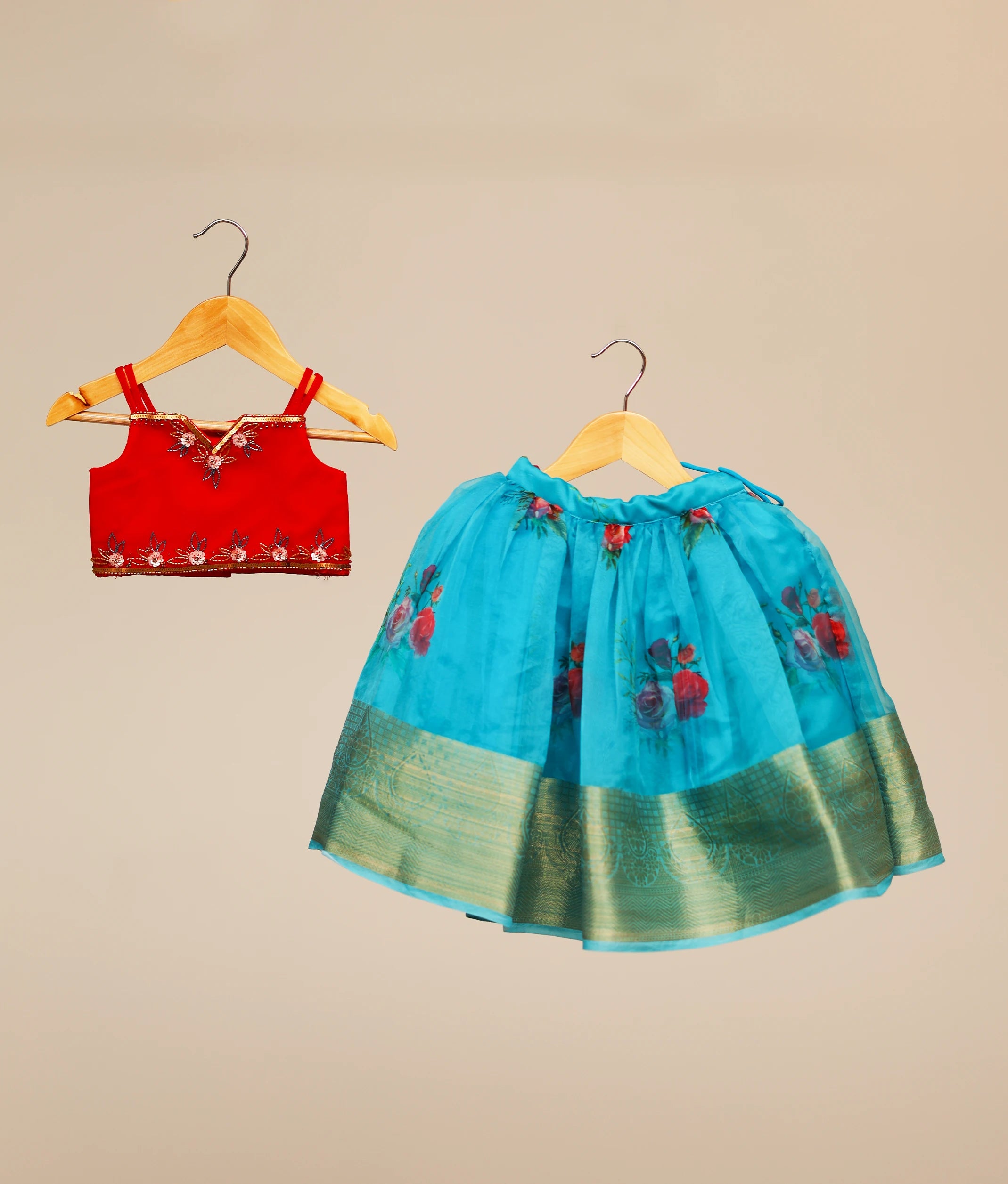 Front view of the red tulle handworked top and sky blue floral organza skirt lehenga set for girls with a broad golden zari border