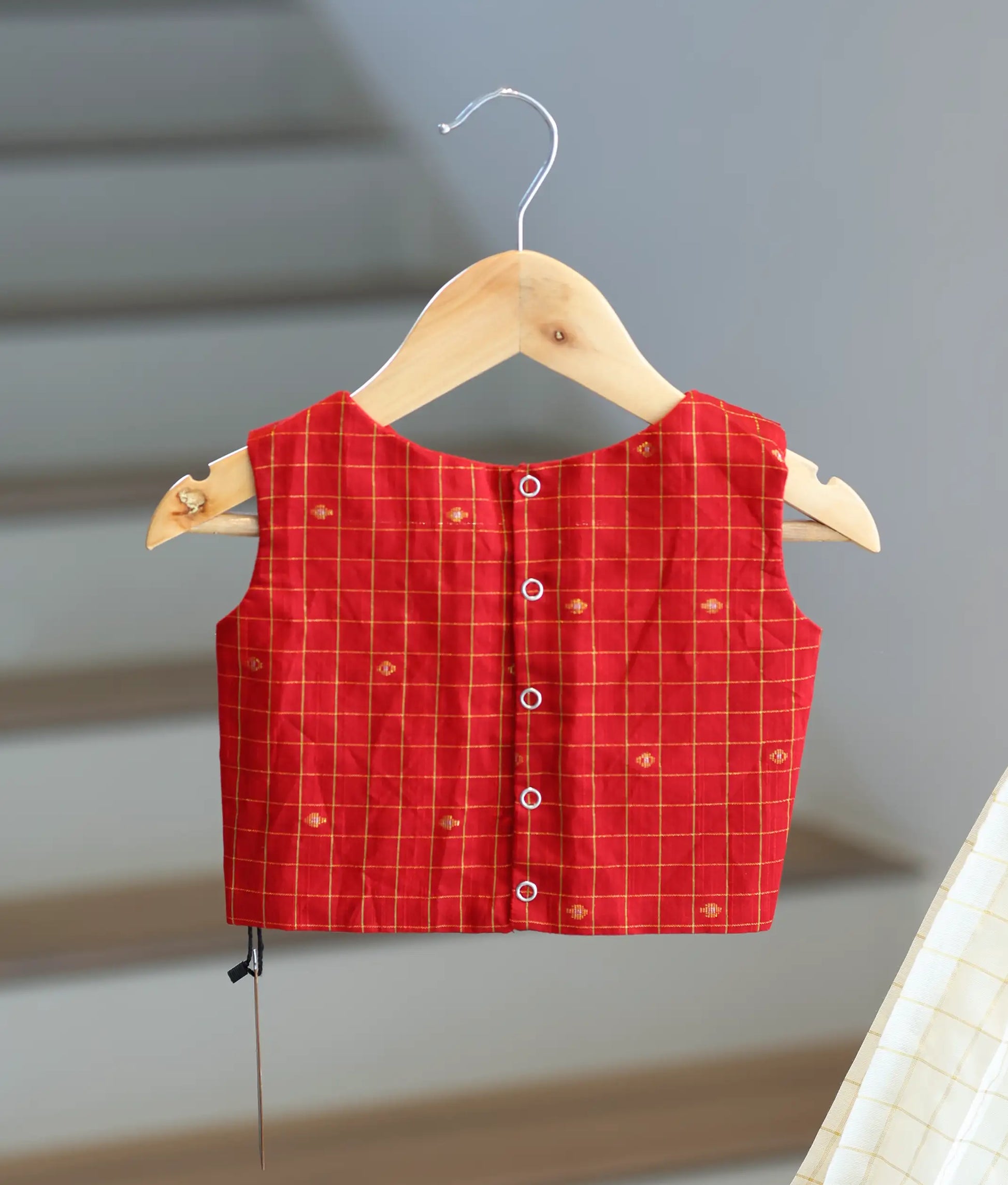 Back view of the red top showing the neat button closures and strap design.