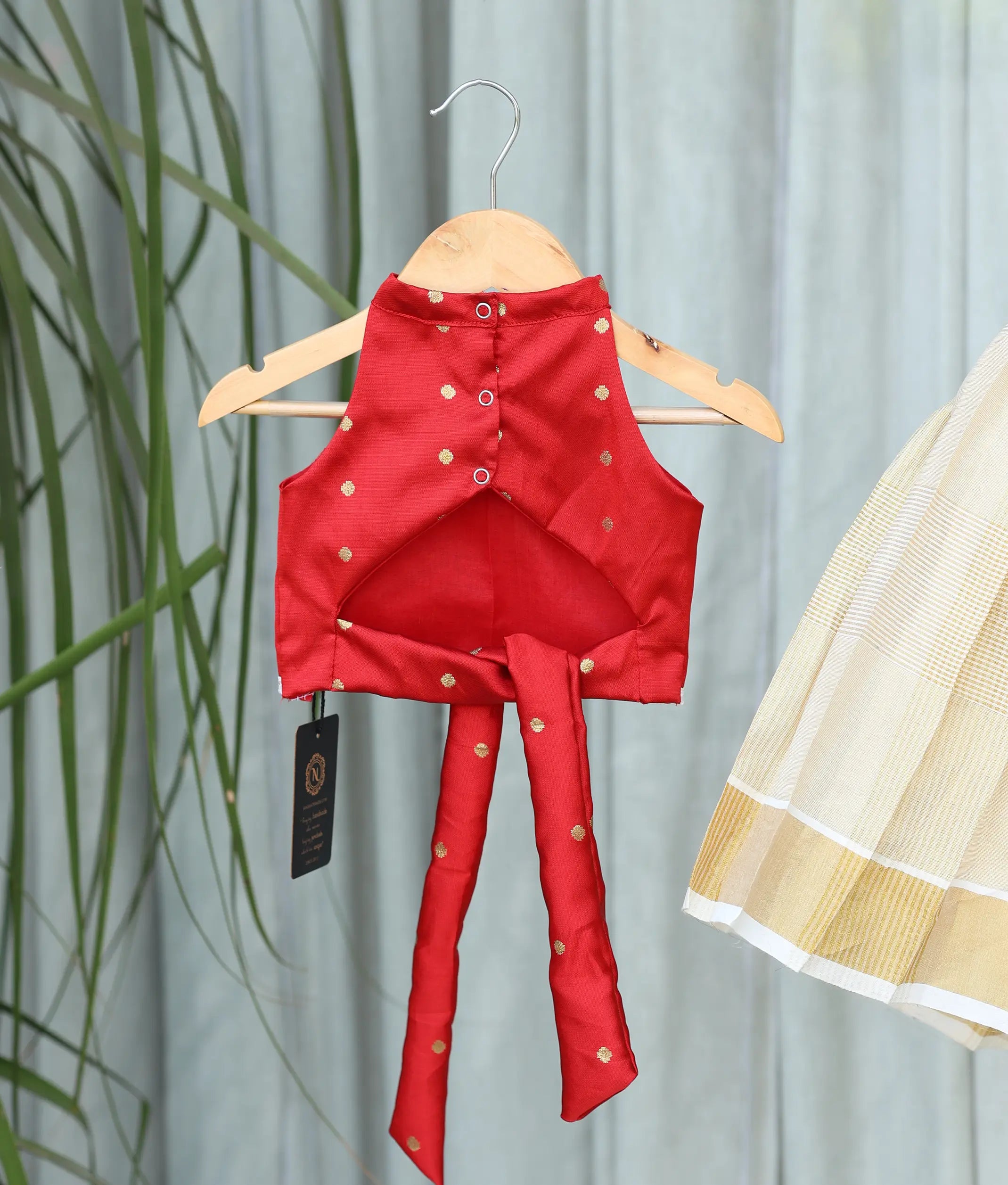 Back view of the red polka dot patterned top showing the neat button closures and a tie.