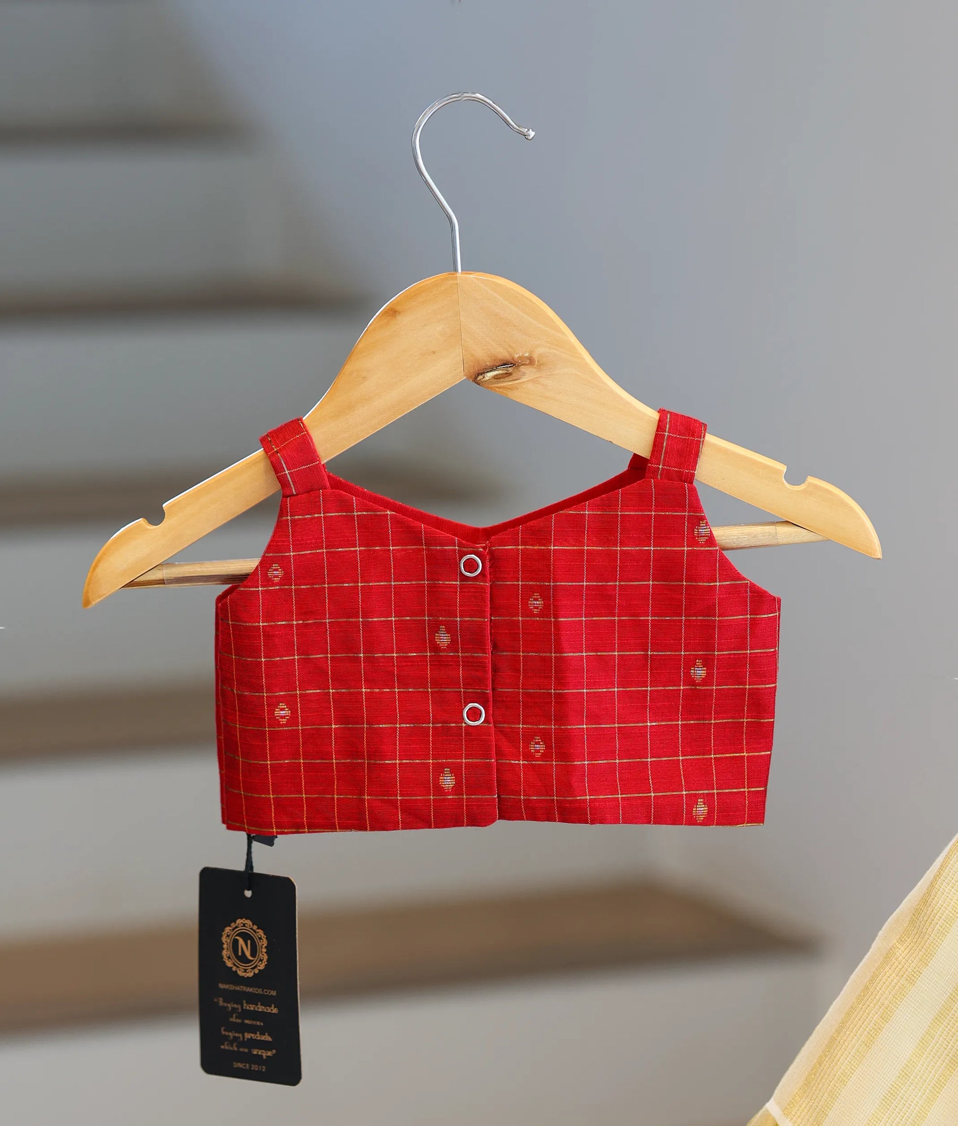 Back view of the red top showing the neat button closures and strap design.