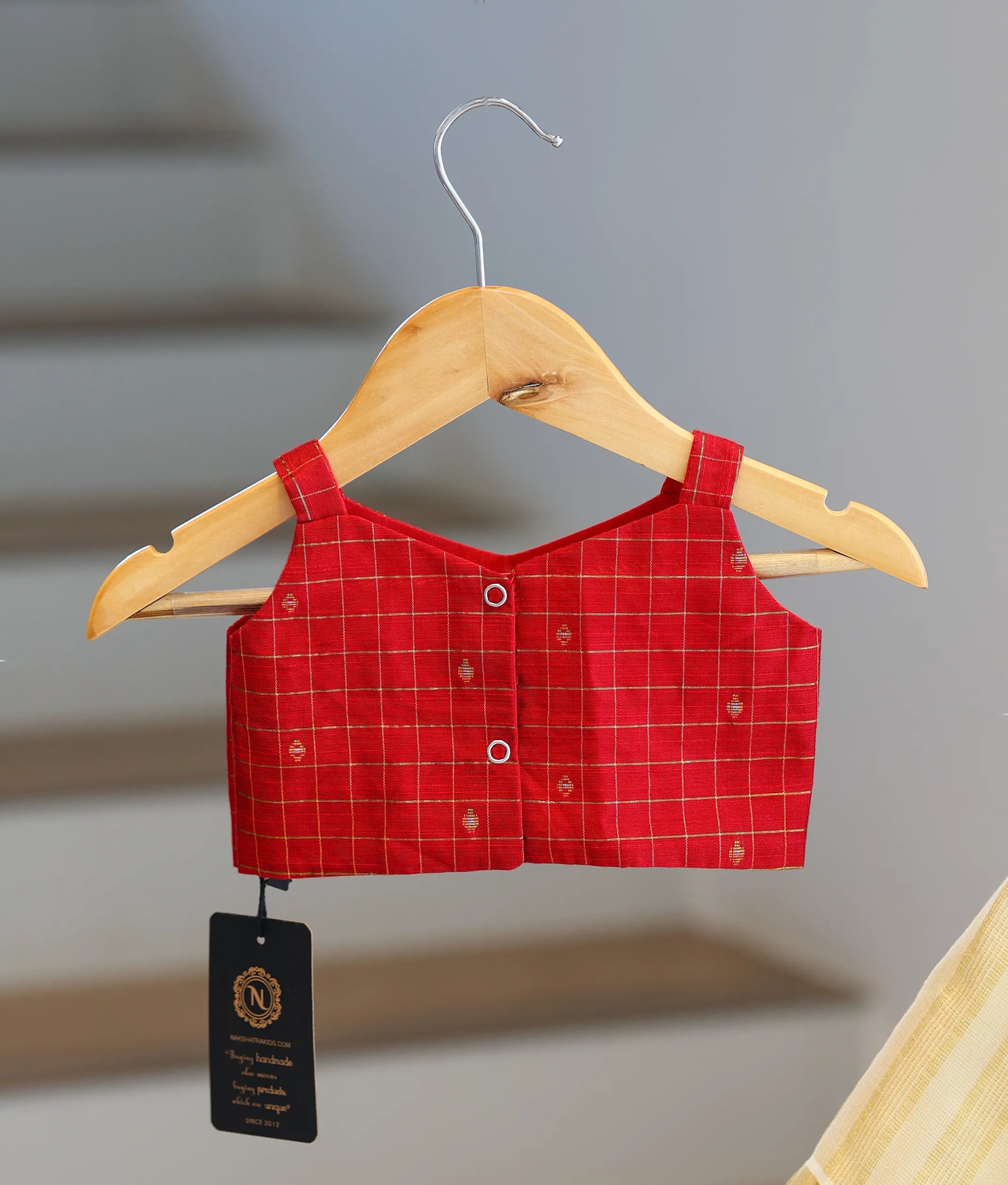 Back view of the red top showing the neat button closures and strap design.