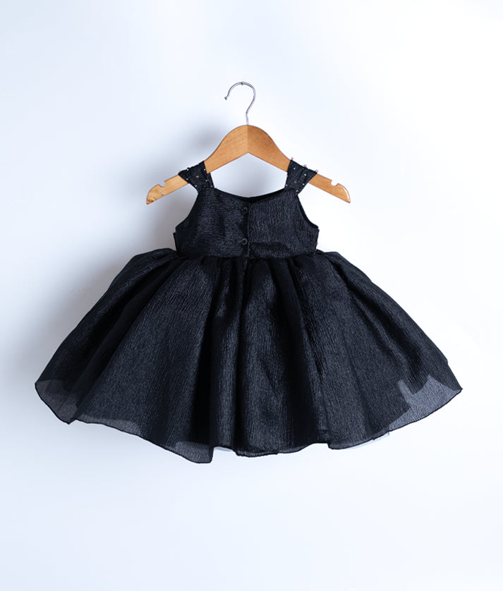 Back view of the black crush organza frock highlighting the round neckline and simple button closure