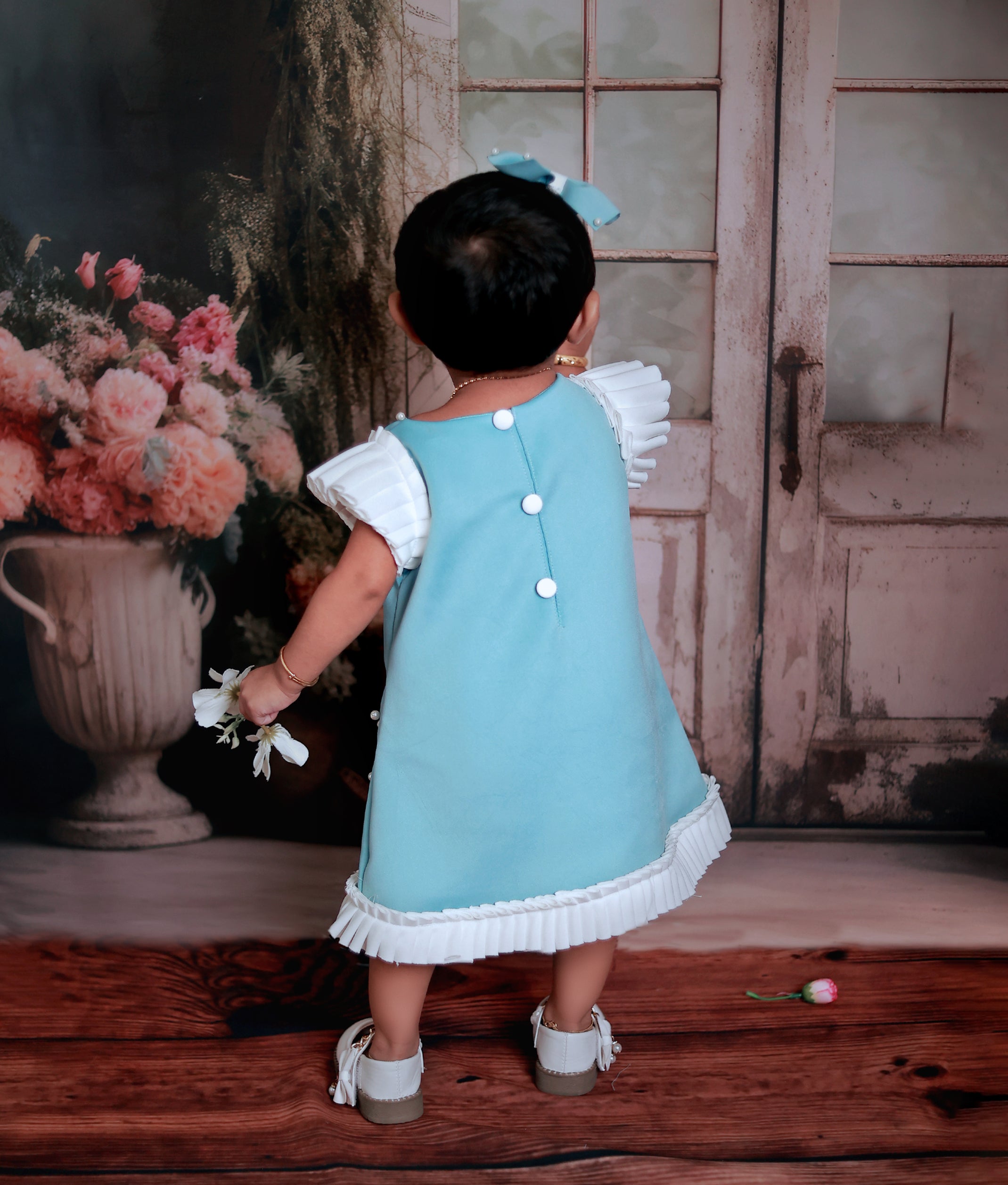 Back view of the blue mermaid theme frock highlighting the round neck and decorative show button closure