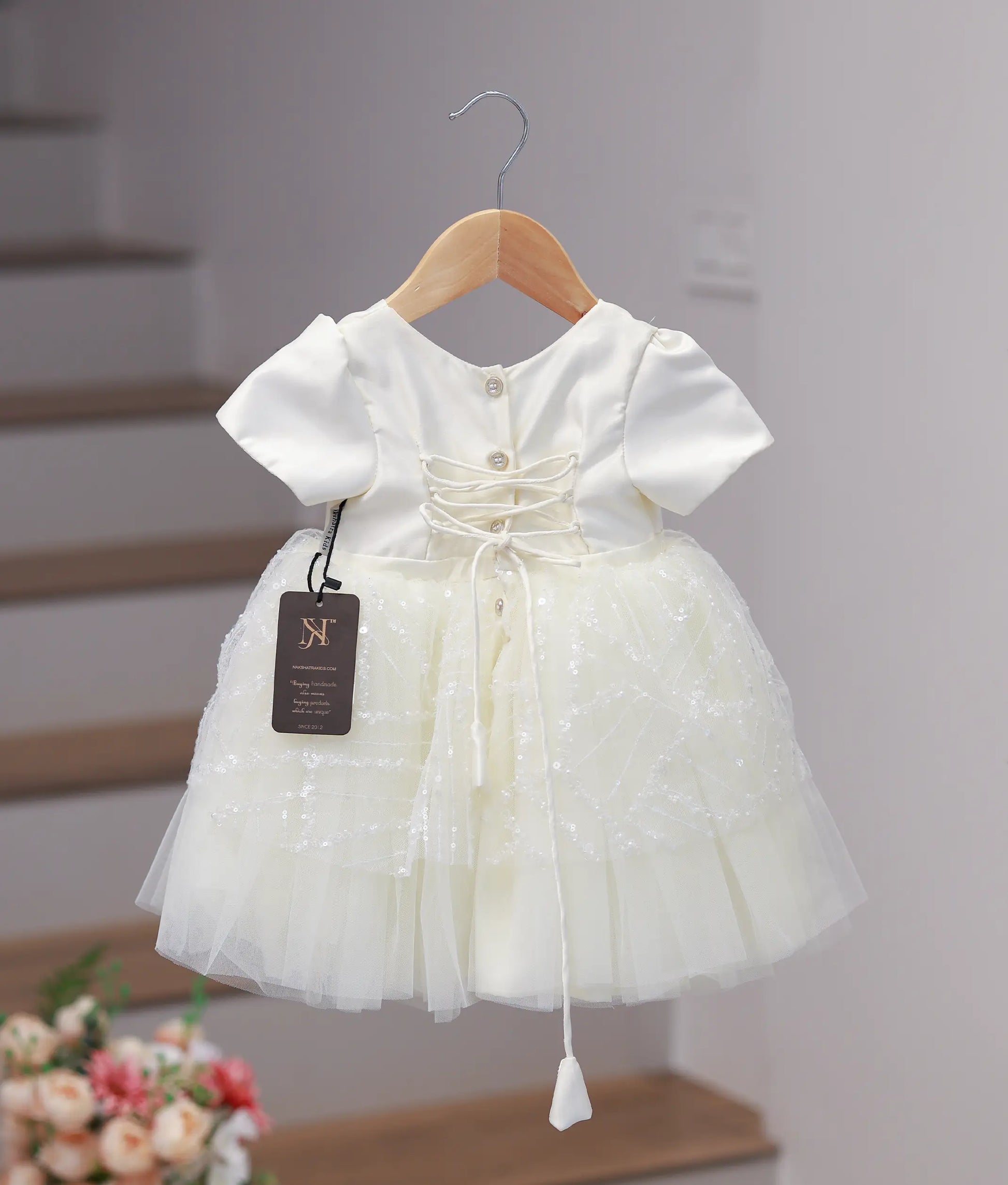 Back view of the off-white work material frock featuring a round neck and a classic tie-up detail