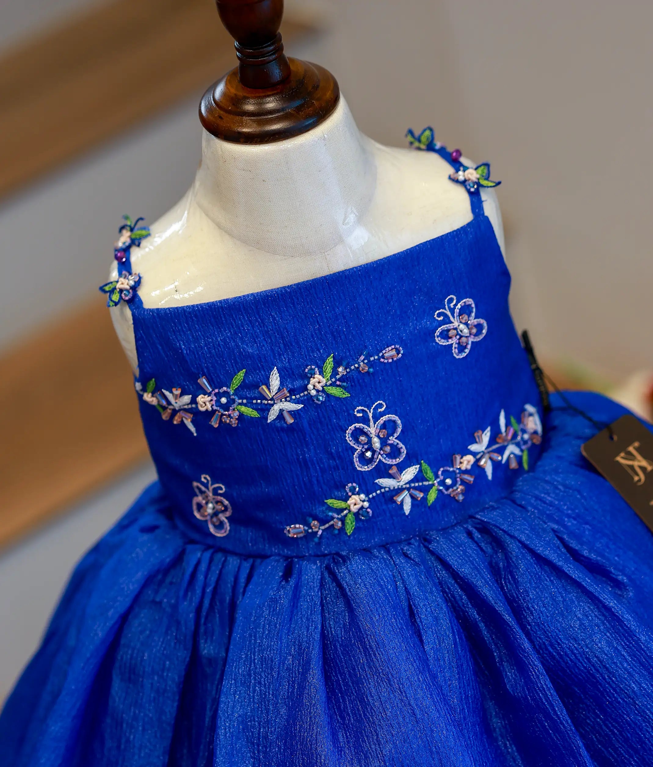 Close-up of the royal blue frock bodice showing the pastel pink and white floral embroidery and shoulder straps