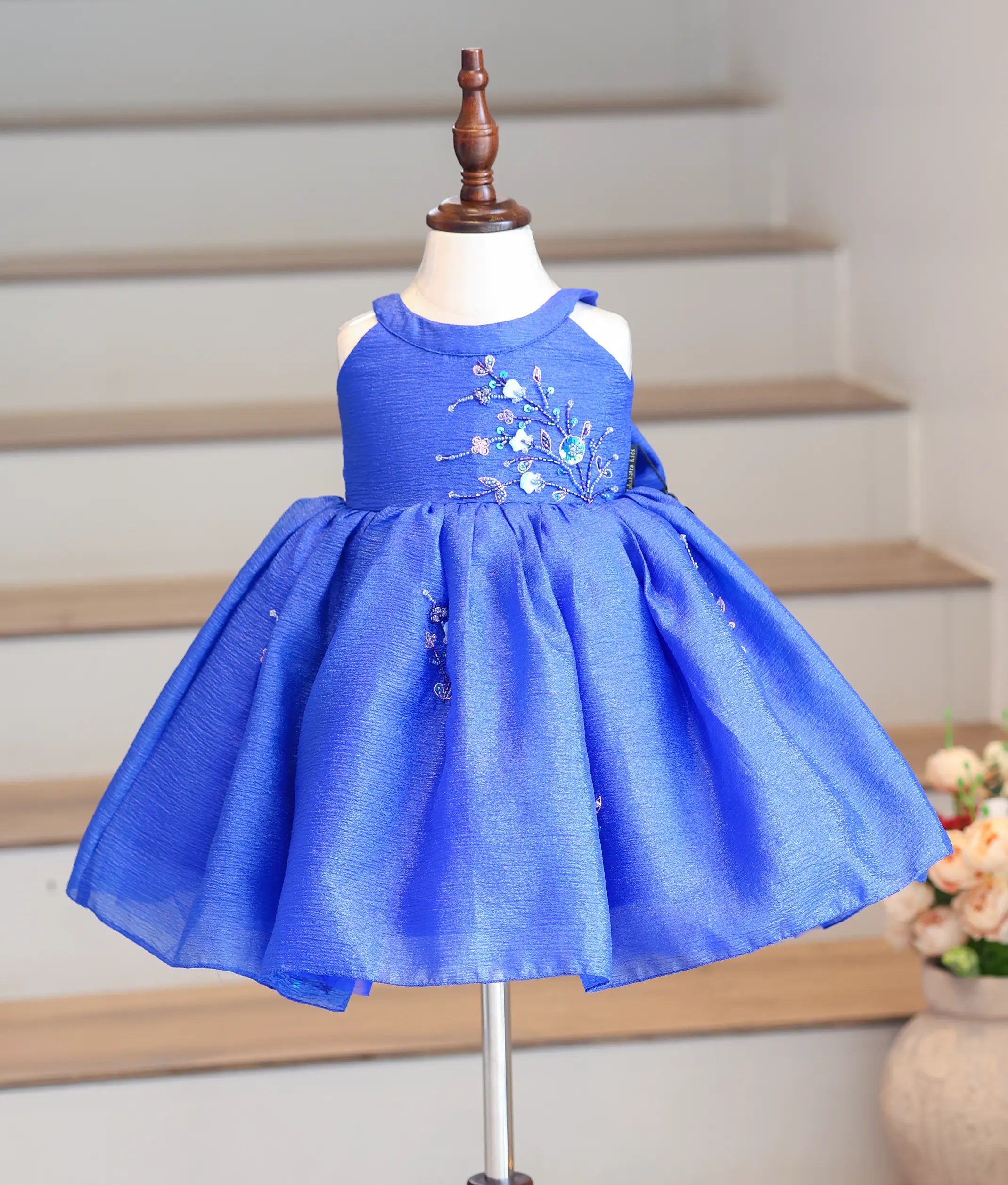 Front view of a royal blue halter neck frock in crush organza with floral handwork.