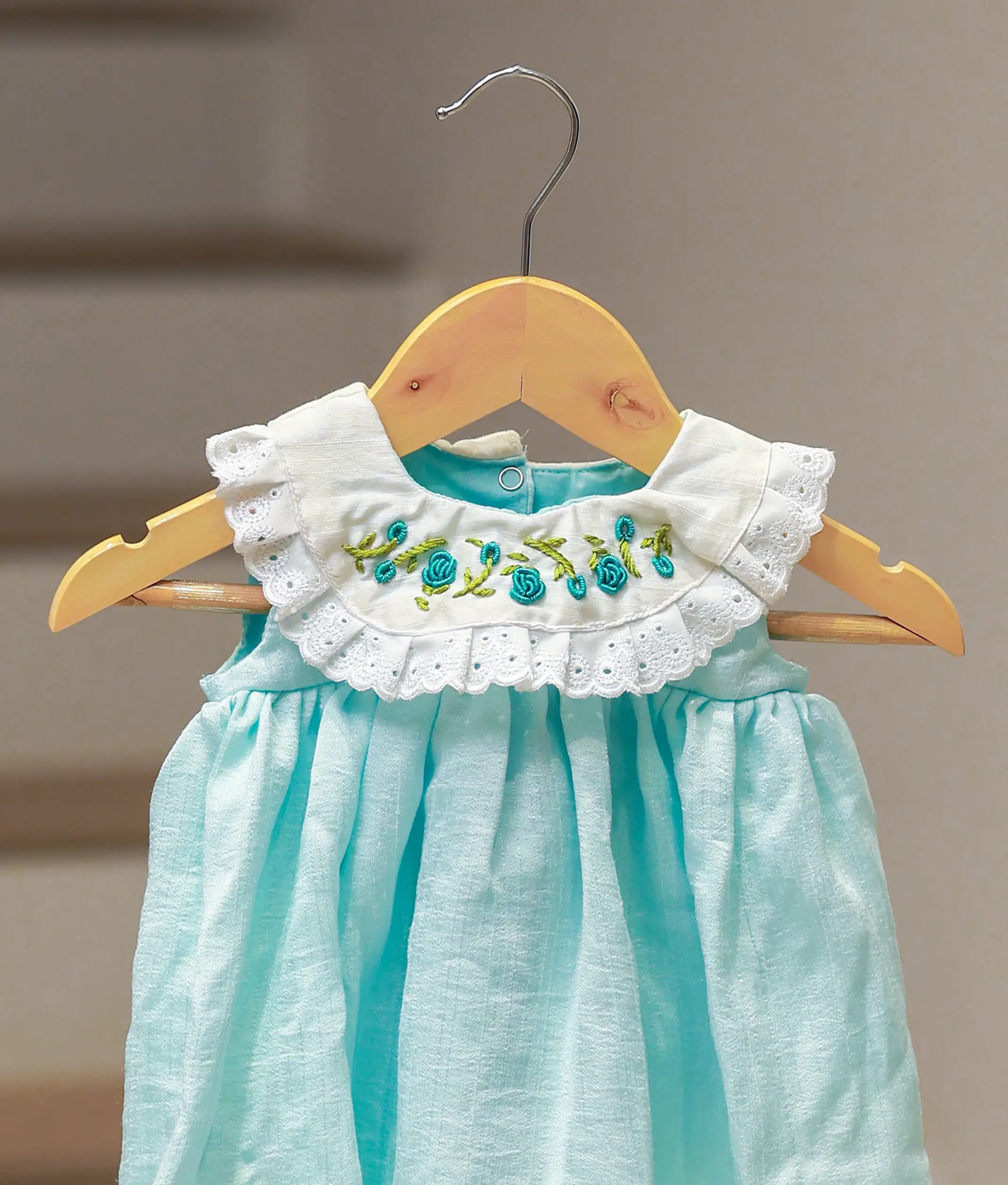 Close-up of the lace detailing and floral embroidery on the sea green cape collar.