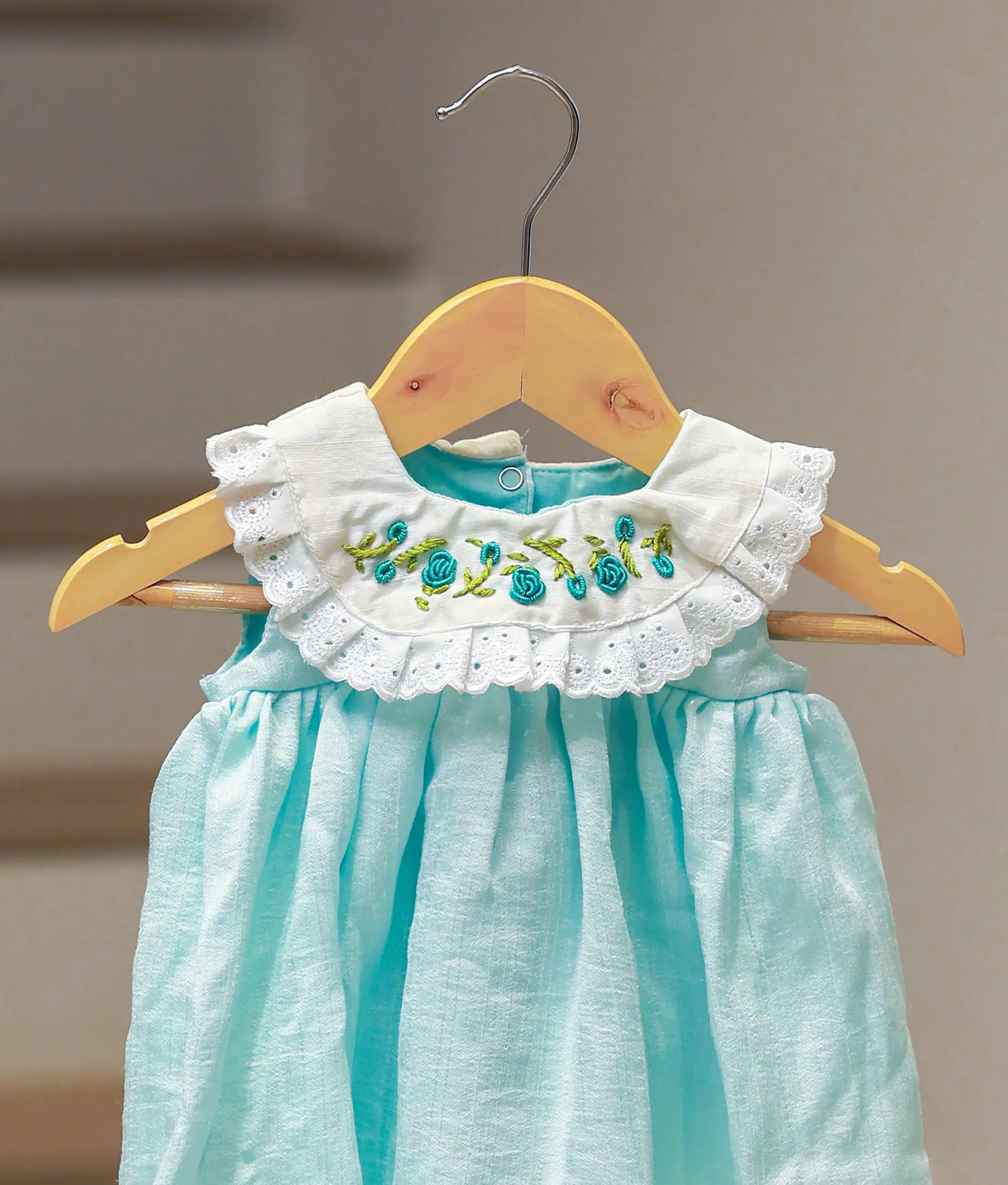 Close-up of the lace detailing and floral embroidery on the sea green cape collar.