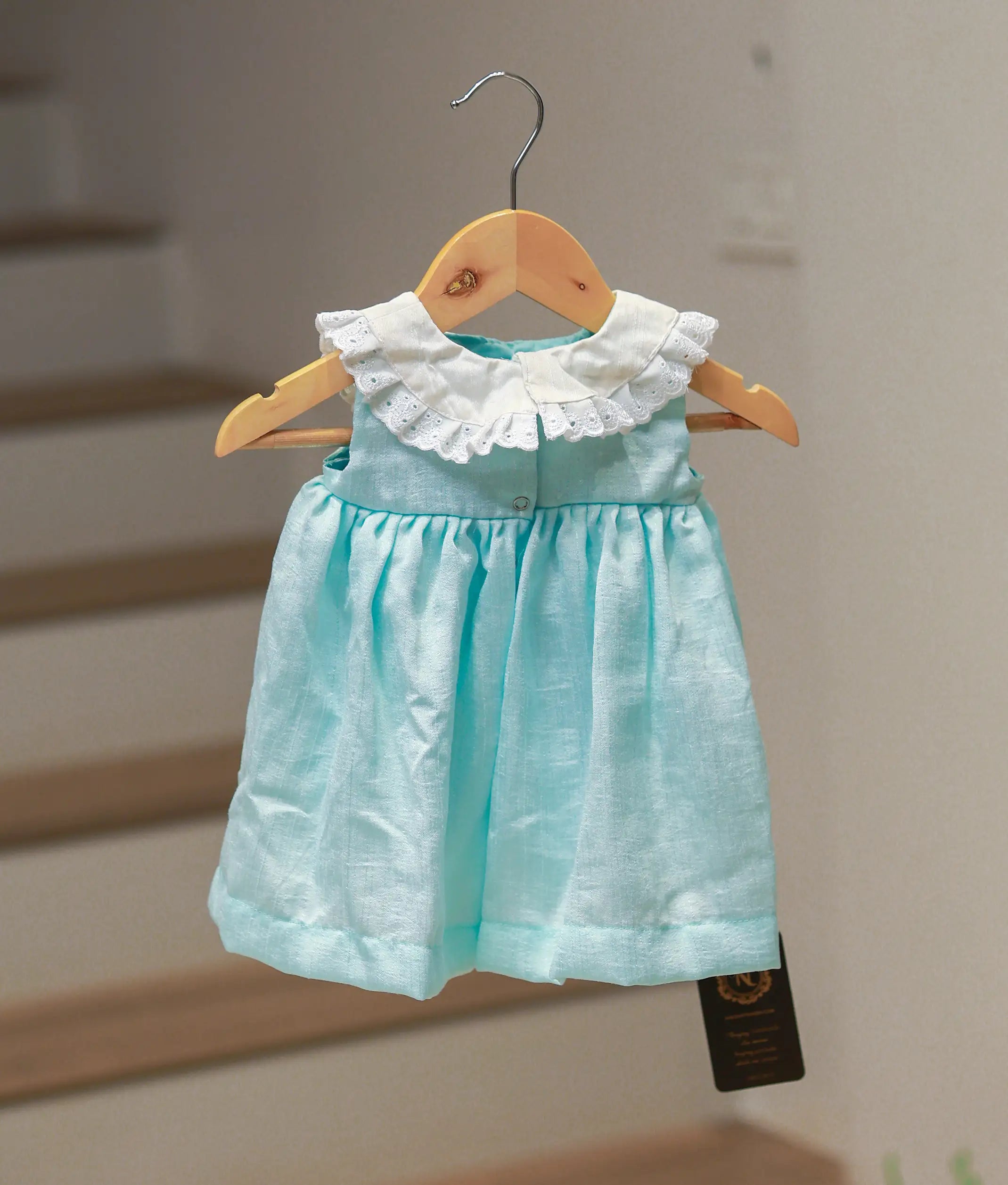 Back view of the sea green frock showing the sleeveless cut and press button closure.