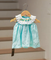 Front view of a sea green sleeveless georgette frock with a floral embroidered cape collar.
