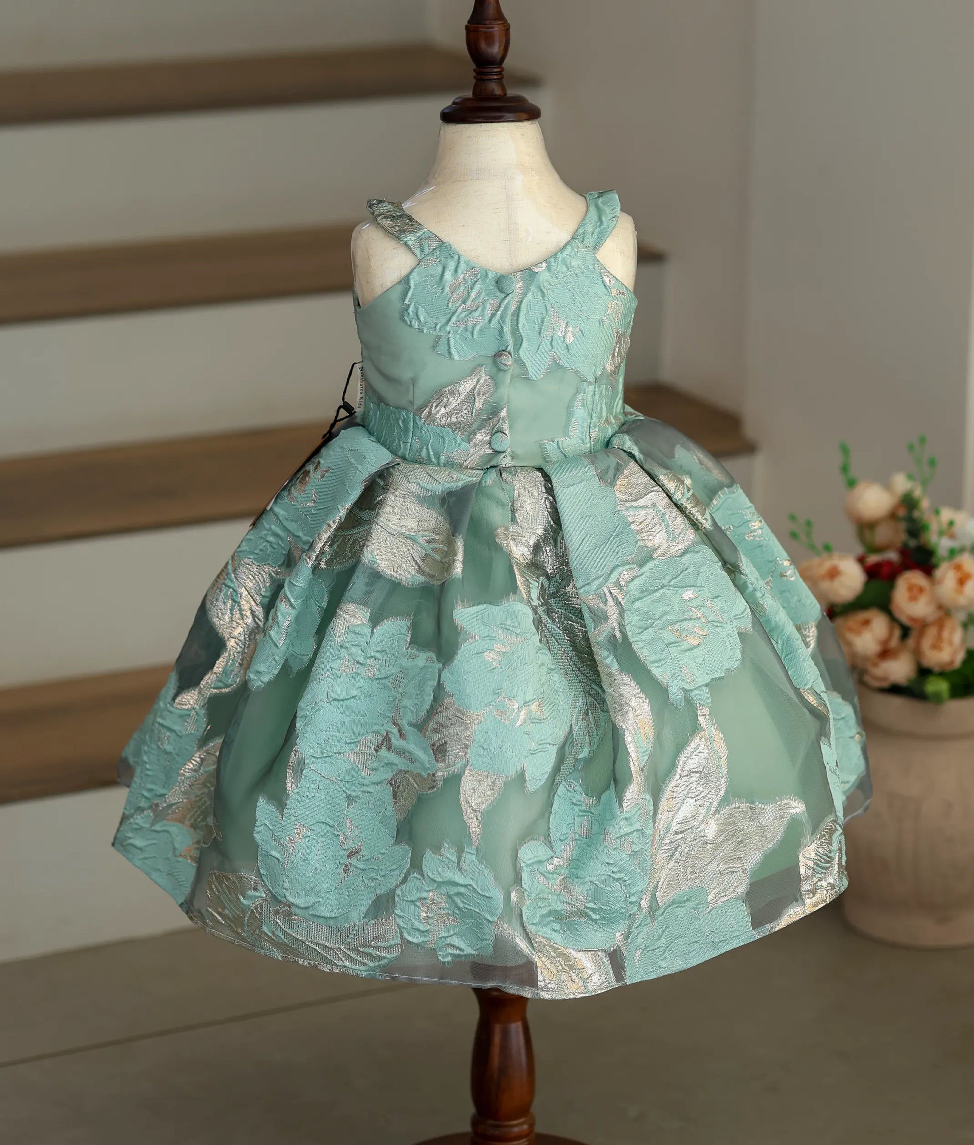 Back view of the sea green frock showing the pleated flair and button closure.
