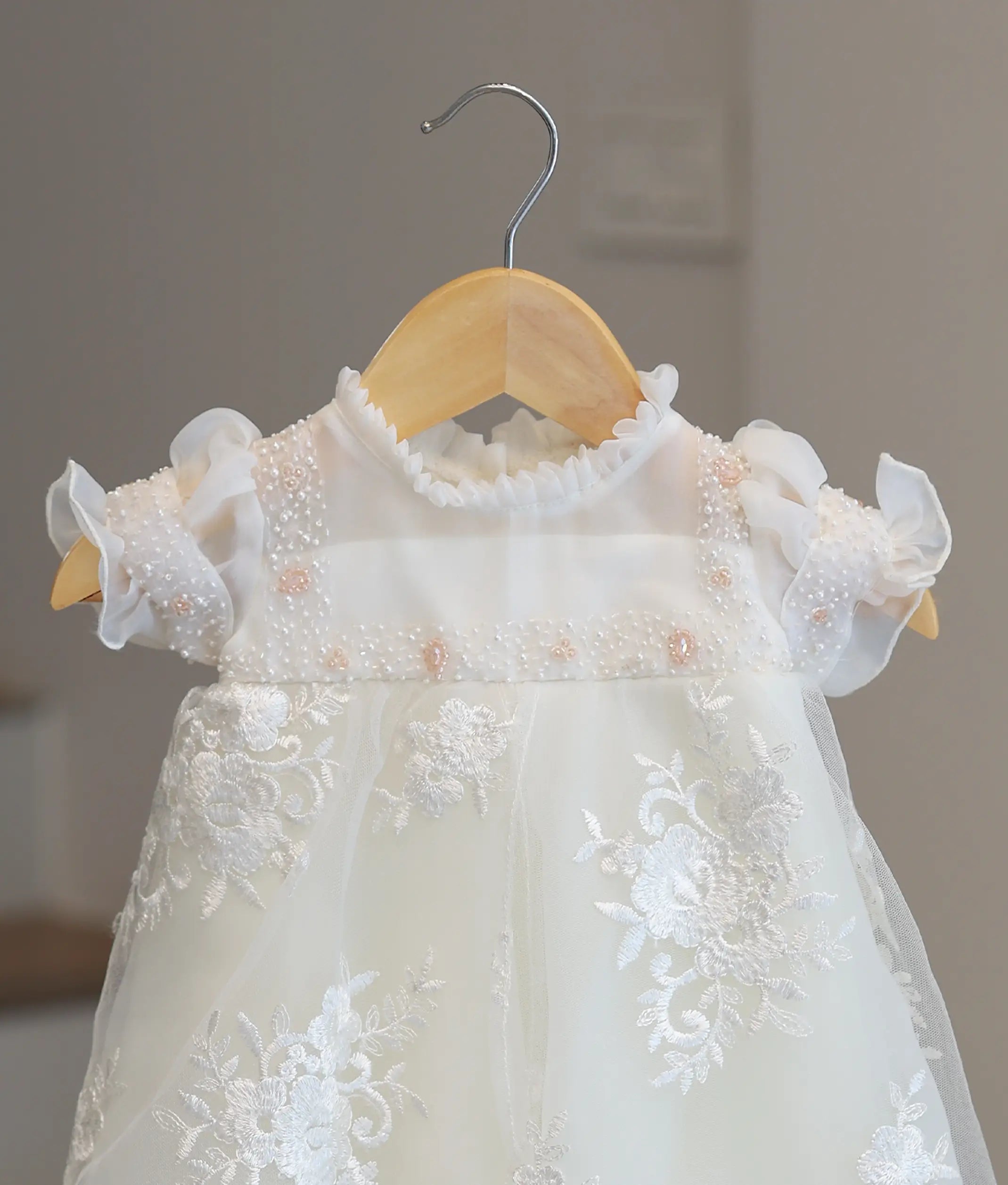 Close-up of premium off-white organza fabric and intricate hand-embroidery on a boutique baby girl christening frock
