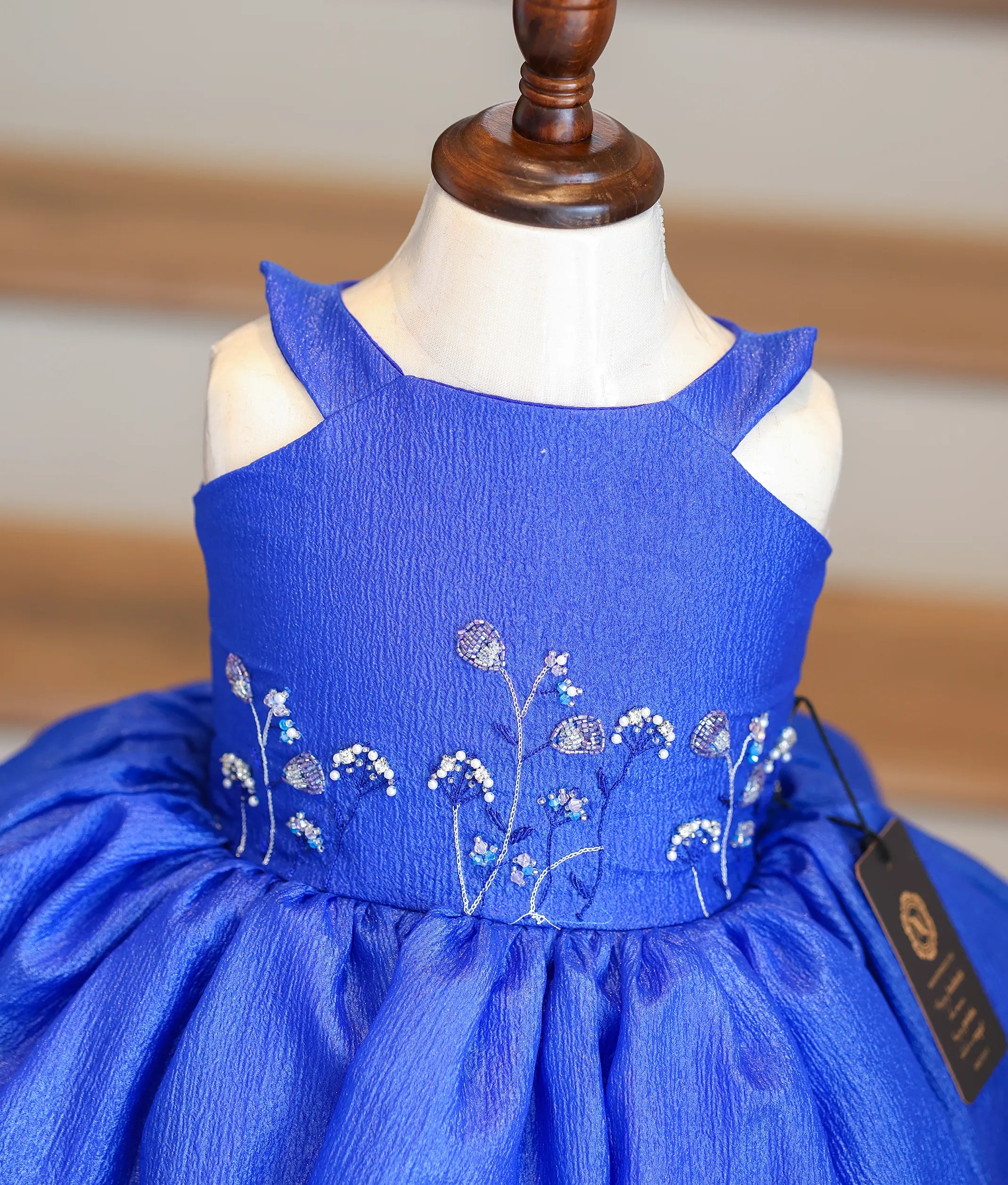 Close-up of the silver and light blue beadwork on the royal blue bodice and scalloped hem.