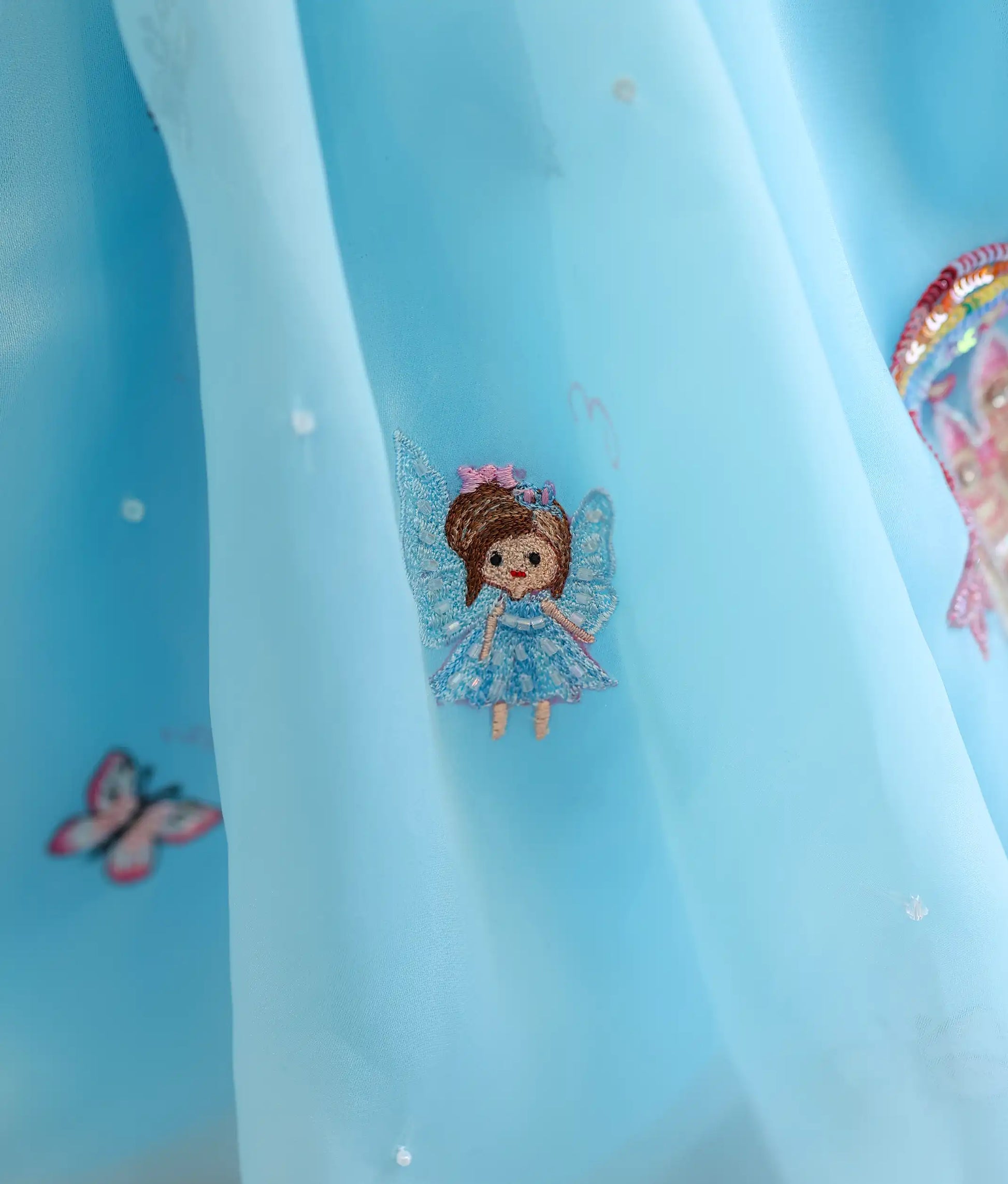 Fairy embroidery detail on a sky blue plane organza castle-themed birthday frock for baby girl with premium handwork
