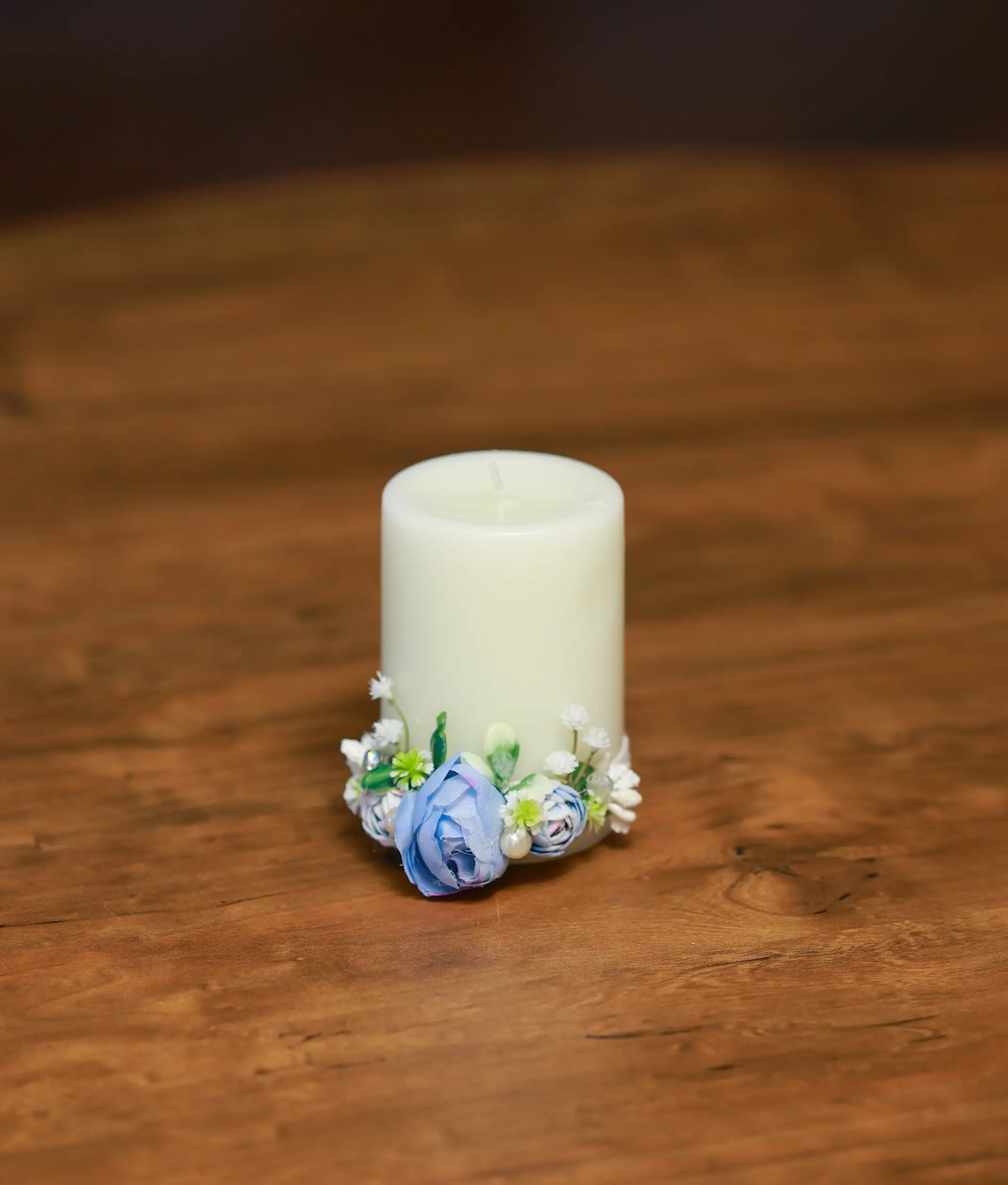 Front view of an ivory decorative baptism candle with a large sky blue rose and white flowers