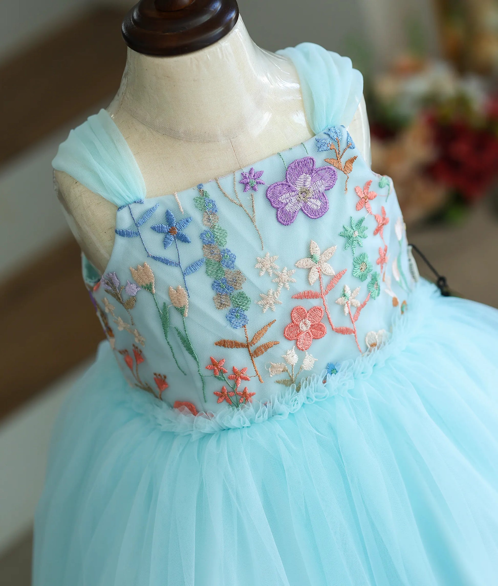 Close-up of the colorful embroidered floral material on the sky blue frock top.