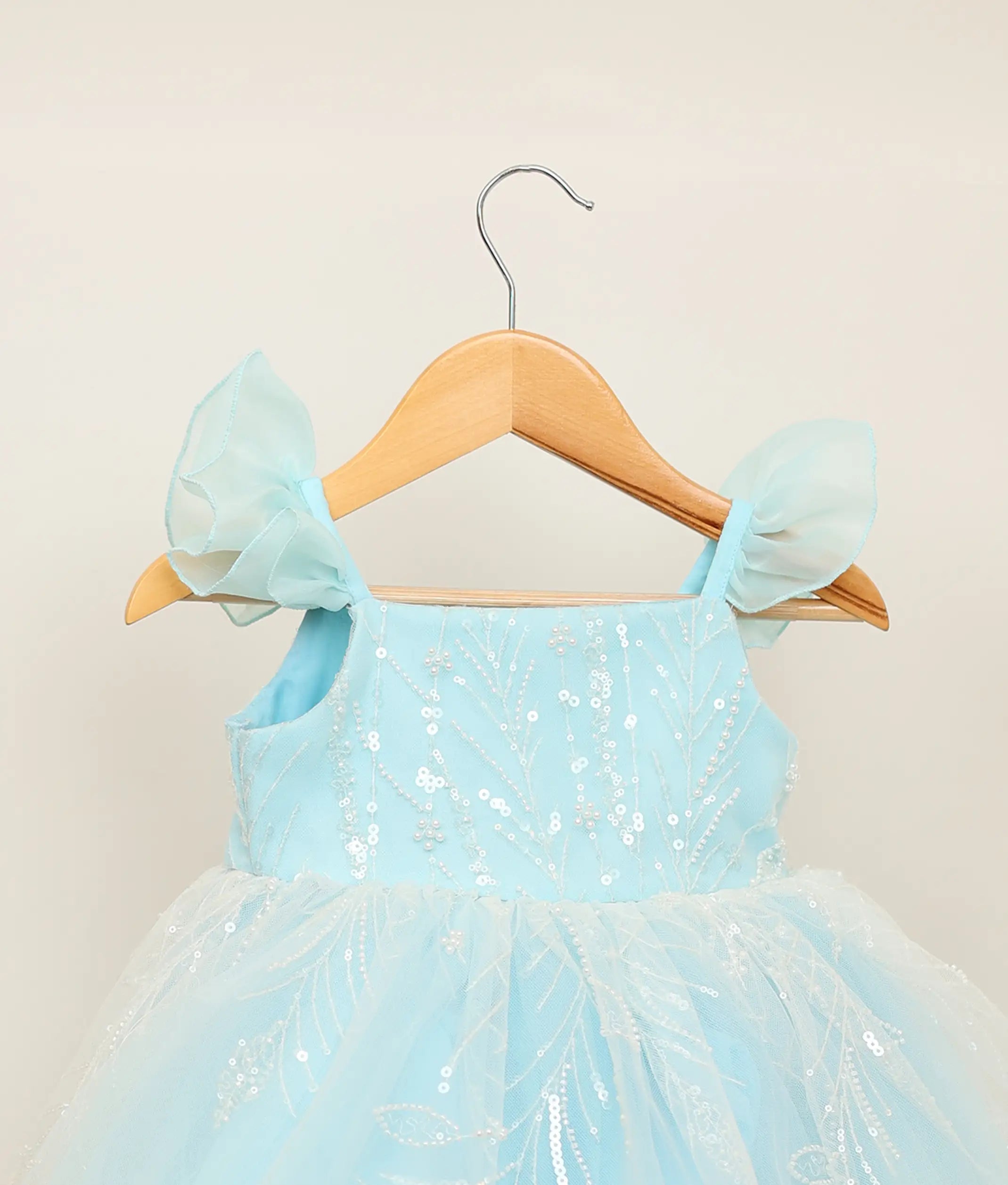 Close-up of the delicate floral vine work material and layered tulle butterfly sleeves on the sky blue birthday dress