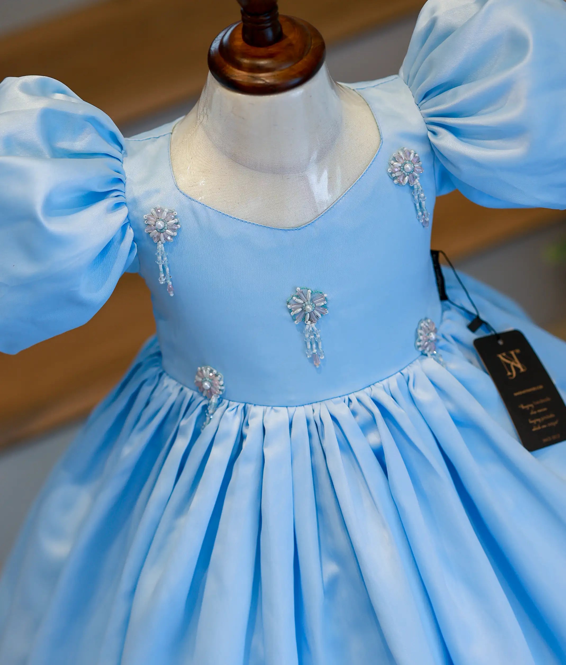 Close-up of the sky blue bodice showing the delicate handwork, floral embellishments, and puff sleeve detail