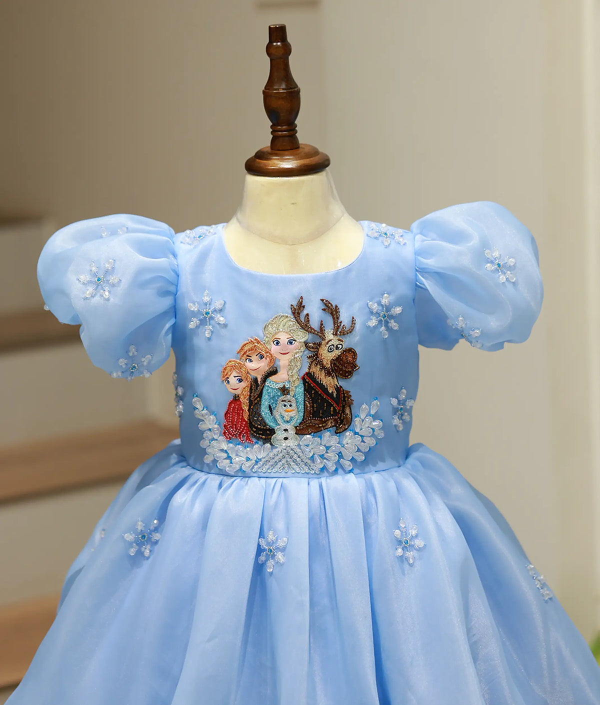 Close-up view of gown top showing hand-painted Elsa, Anna, and Olaf artwork surrounded by snowflake beadwork.