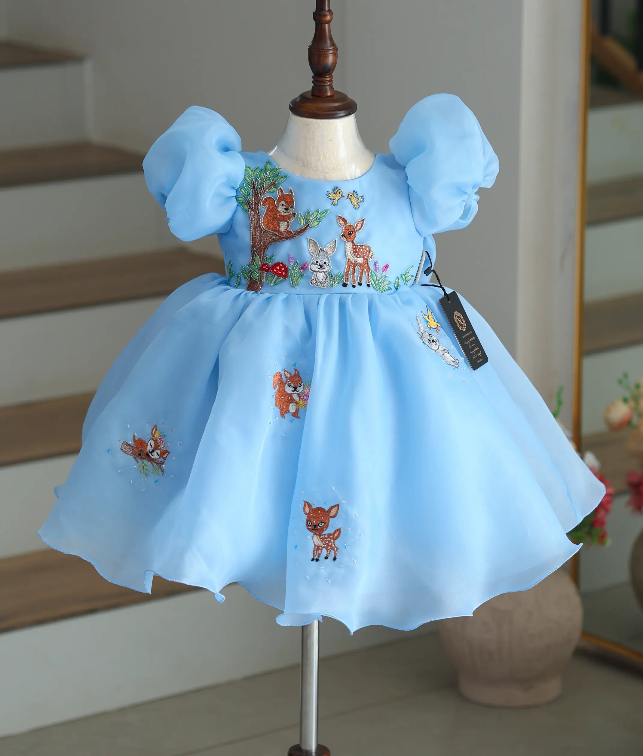 Front view of a sky blue organza frock with jungle animal handwork.