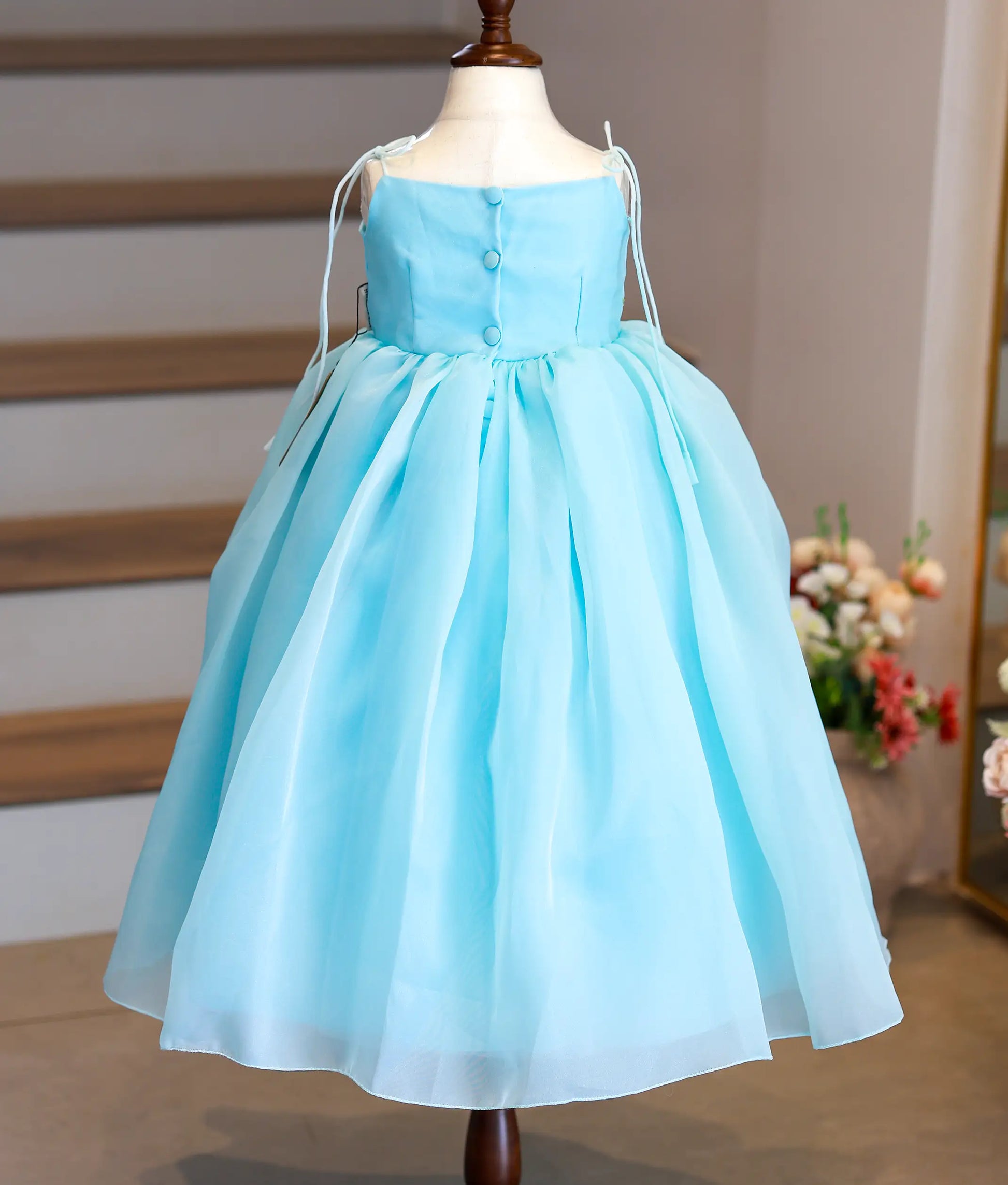 Back view of sky blue organza gown showing the square neckline and the elegant show button closure