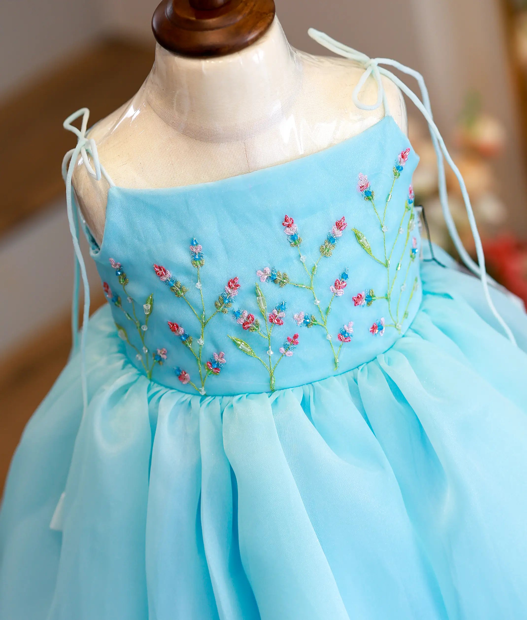 Close-up of the delicate pink and white floral handwork and the tie-up shoulder strap detail on the sky blue organza gown