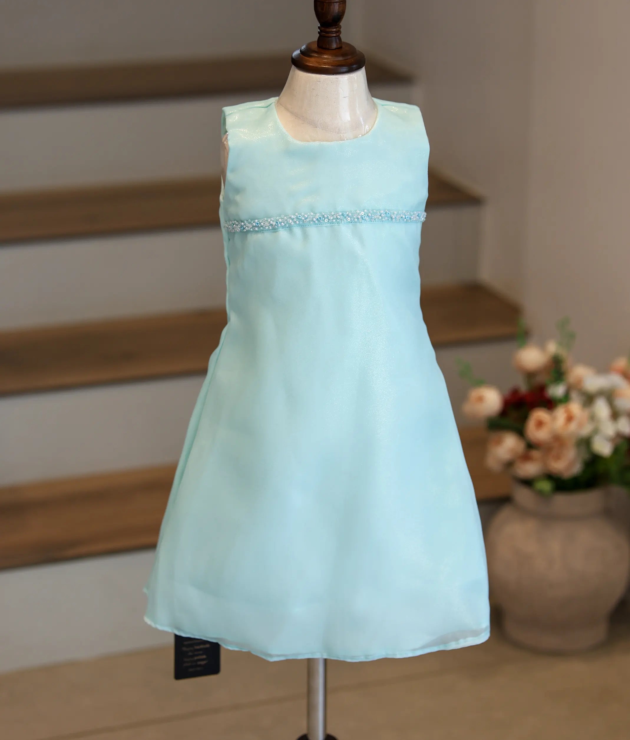 Front view of a sky blue shimmer organza A-line frock with a horizontal handworked line.