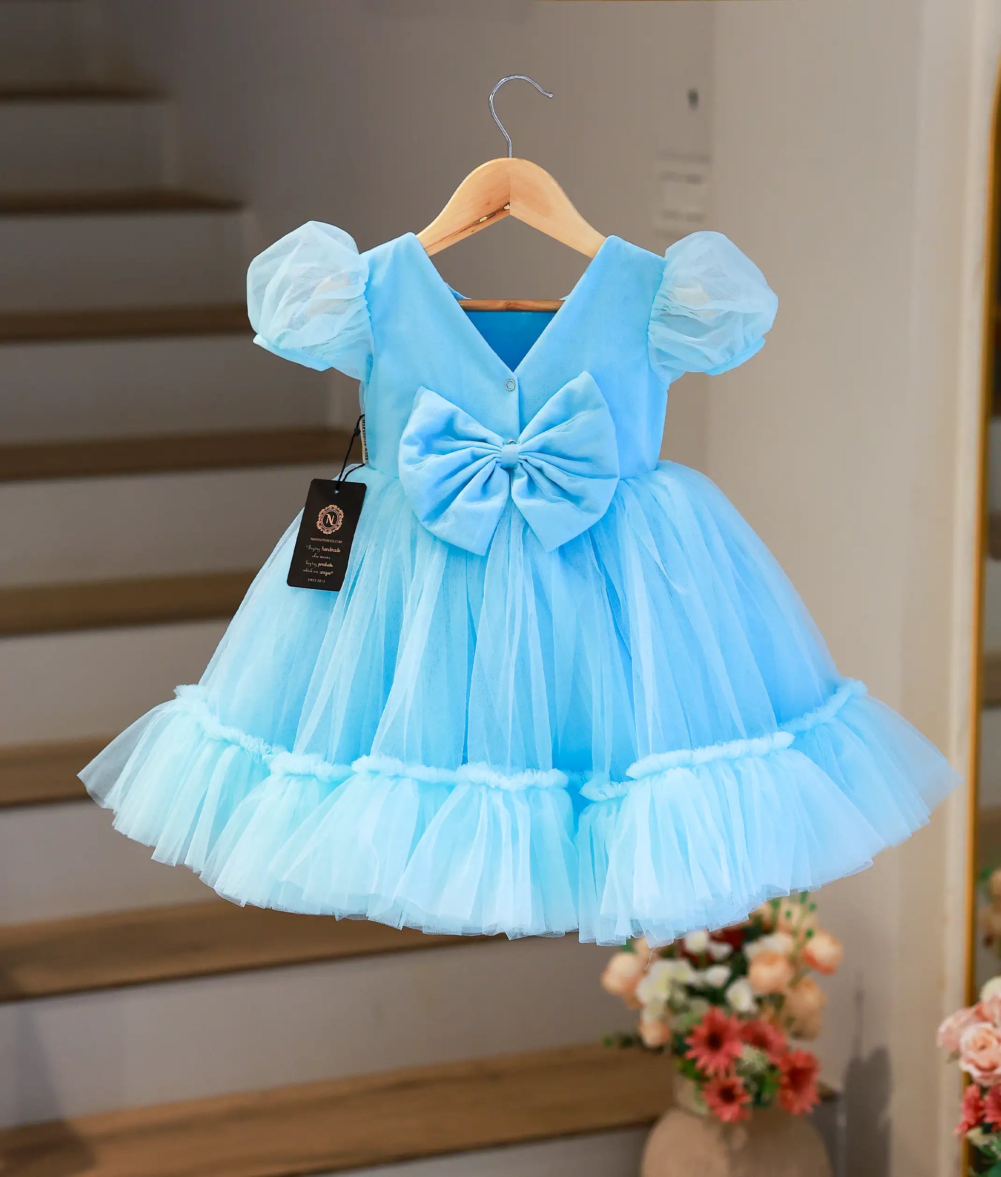 Back view of the sky blue party frock showing the large statement bow and elegant V-neck back design.